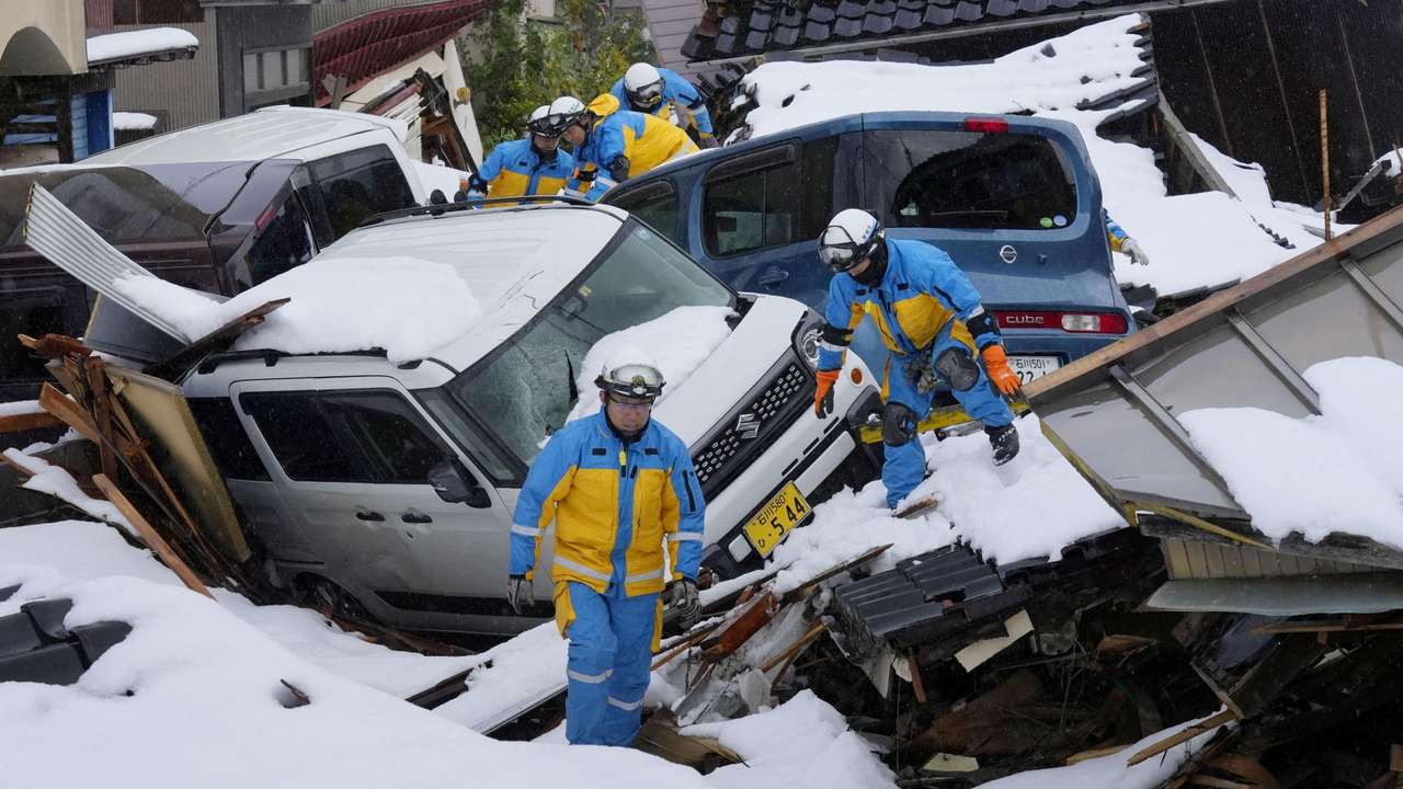 Police officers search for victims in snow-covered residential area devastated by tsunami following earthquake, in Suzu