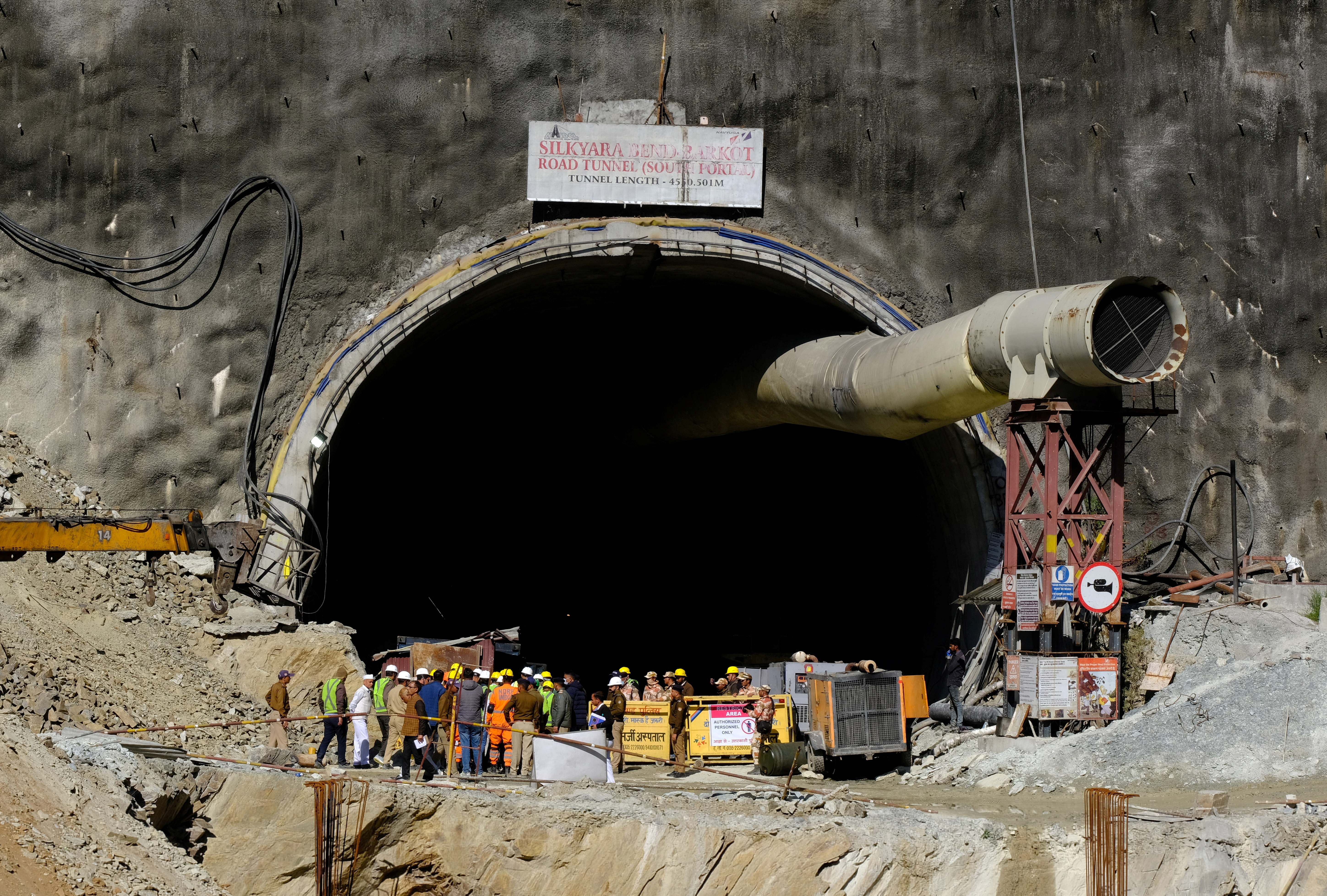 Members of rescue teams stand at the entrance of a tunnel where 40 road workers are trapped after a portion of the tunnel collapsed, in Uttarkashi
