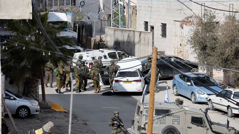 Israeli troops stand guard near a shooting scene in Hebron