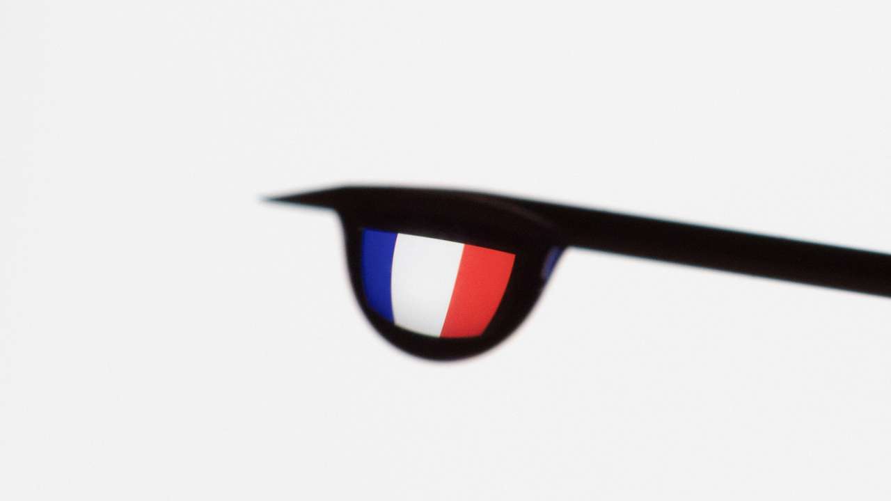 Illustration shows the flag of France reflected in a drop from a syringe needle
