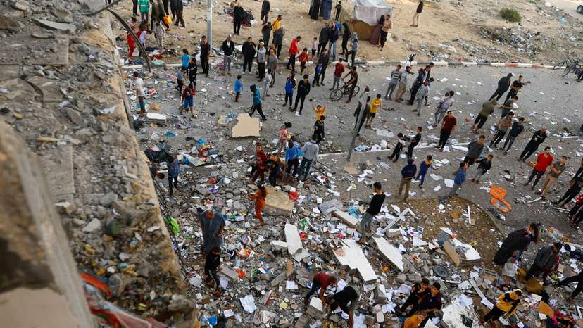 People walk among debris at the site of an Israeli strike on the apartment building, in Khan Younis