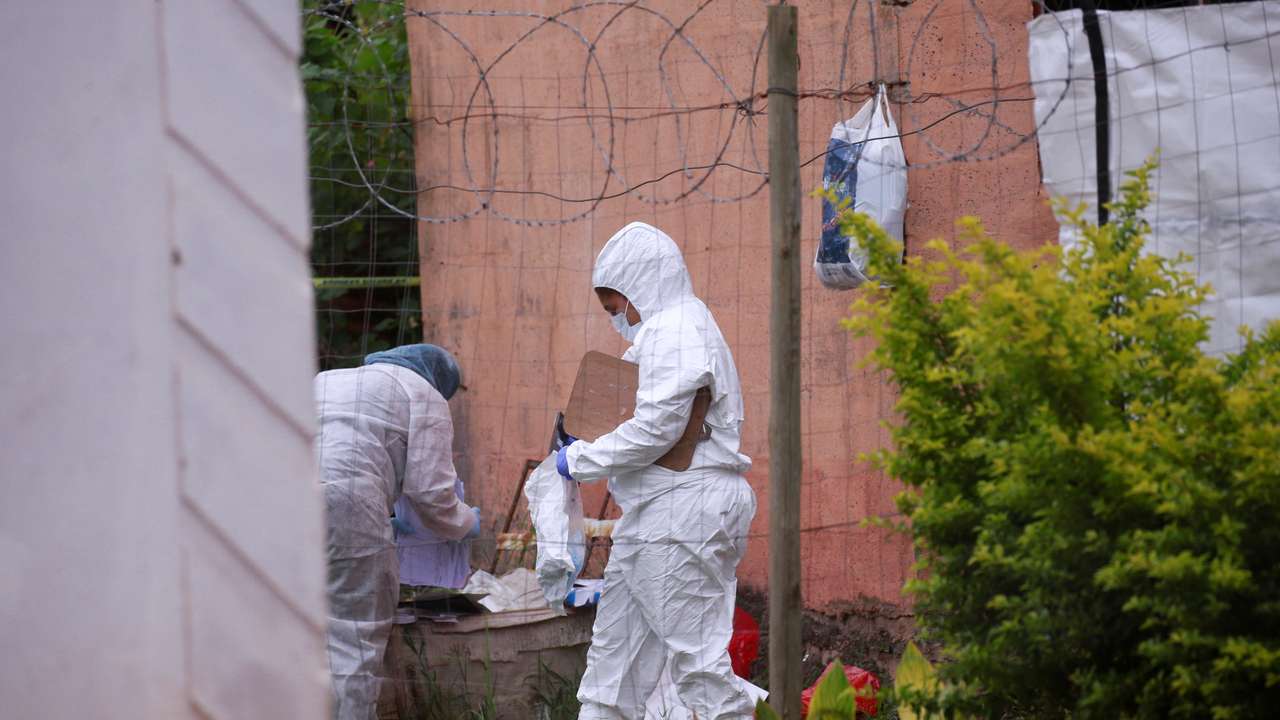 Forensic workers examine the scene where suspected criminals were killed during a police raid in Marianhill near Durban