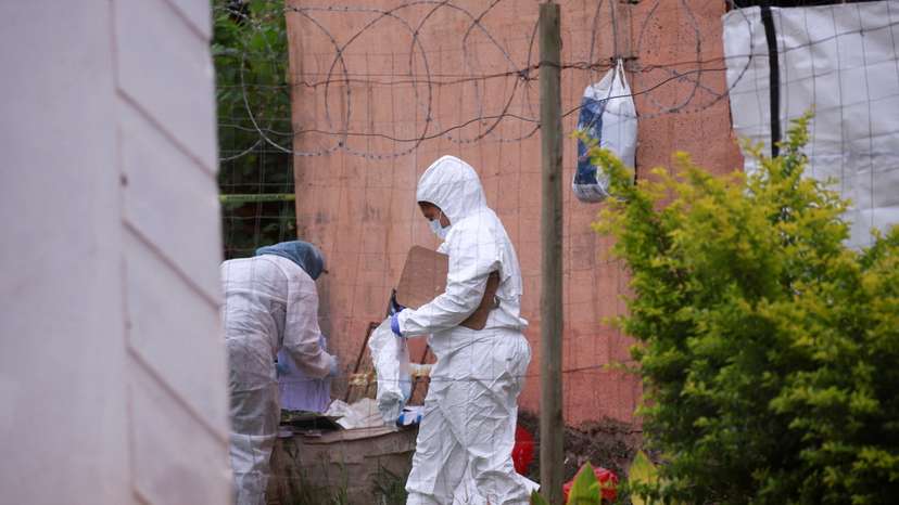 Forensic workers examine the scene where suspected criminals were killed during a police raid in Marianhill near Durban