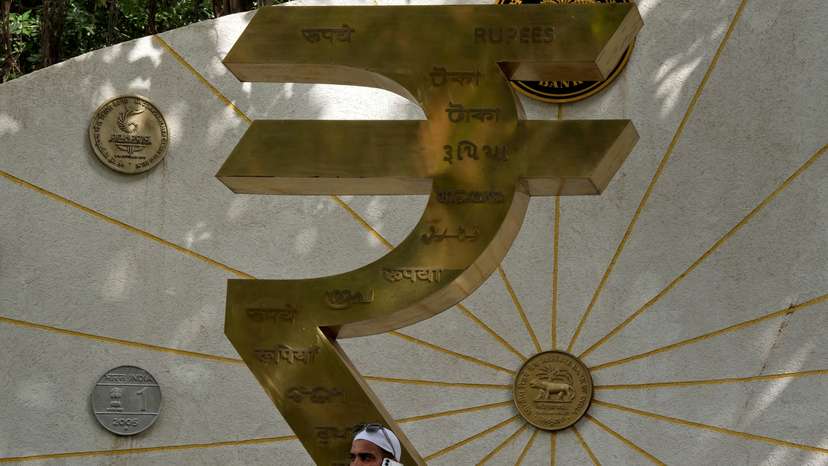 FILE PHOTO: A man speaks on his mobile phone next to an installation of the Rupee logo and Indian currency coins in Mumbai