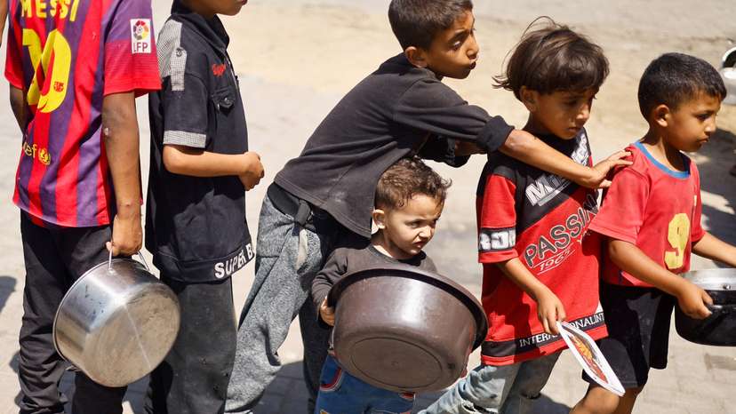FILE PHOTO: Palestinians gather to receive food cooked by a charity kitchen, amid food scarcity, as Israel-Hamas conflict continues, in Khan Younis in the southern Gaza Strip