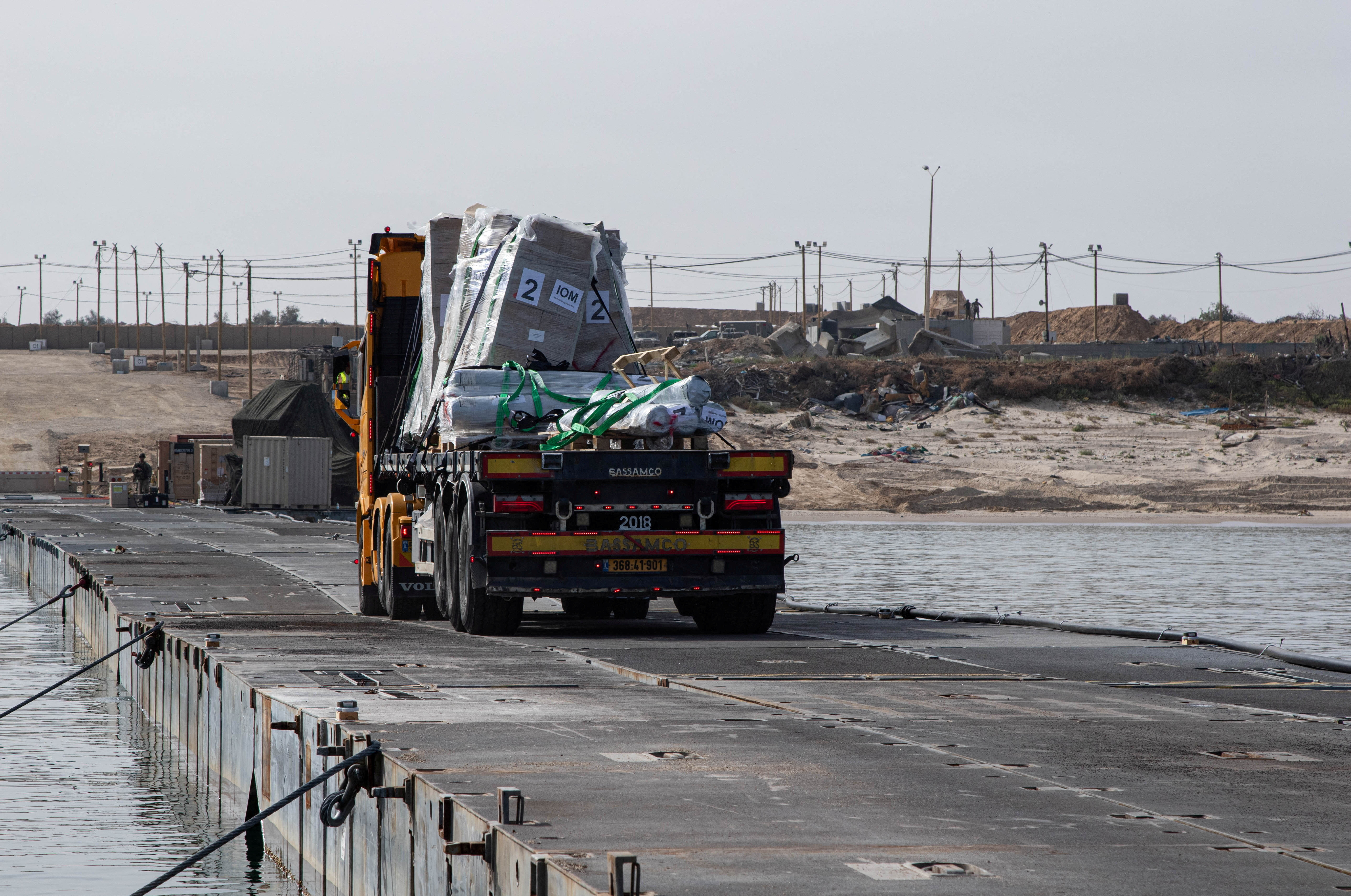 FILE PHOTO: Trucks deliver humanitarian aid over a temporary pier on the Gaza coast