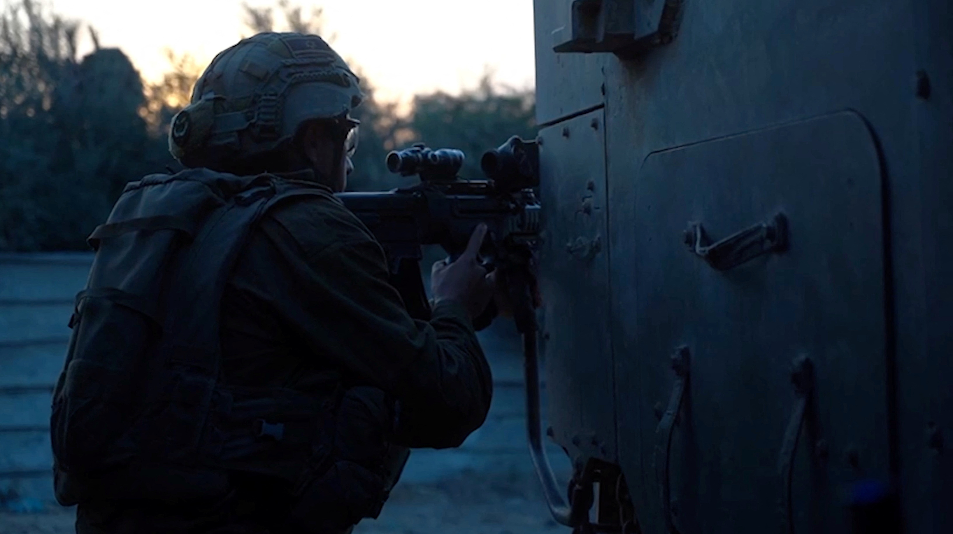 An Israeli soldier holds a weapon from behind a military vehicle in a location given as Gaza