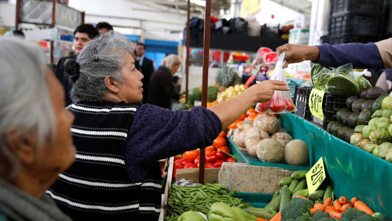 Woman buys tomatoes in a groceries stall at Granada market in Mexico City