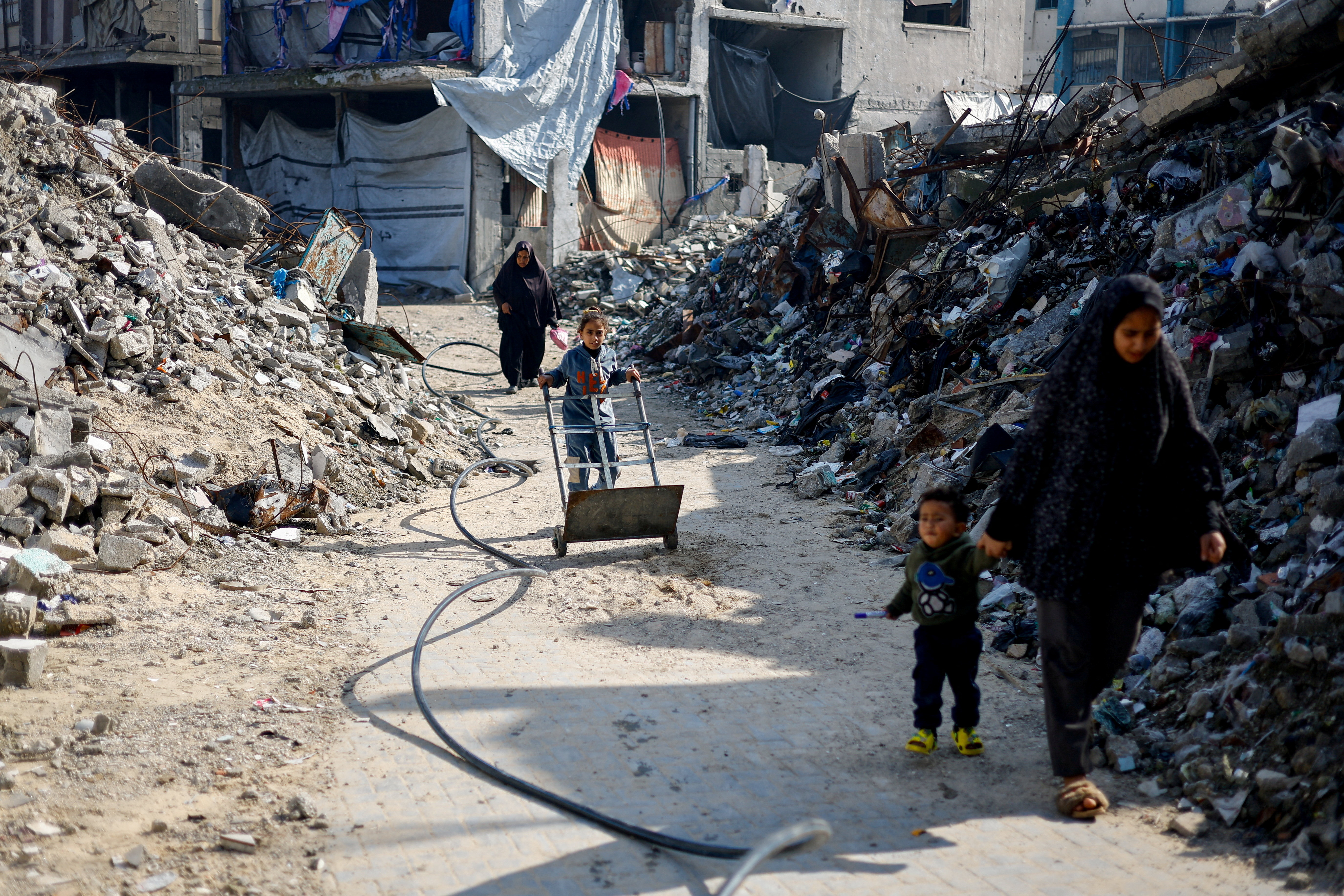 FILE PHOTO: Palestinians walk past the rubble of residential buildings destroyed during the war, in Jabalia