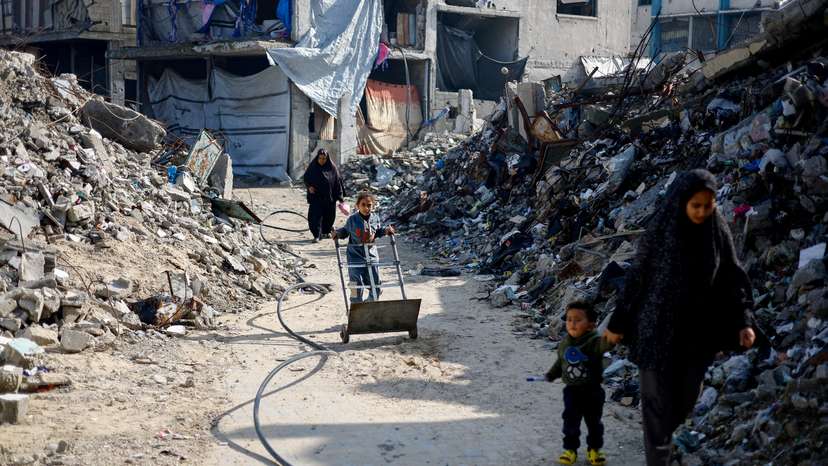 FILE PHOTO: Palestinians walk past the rubble of residential buildings destroyed during the war, in Jabalia