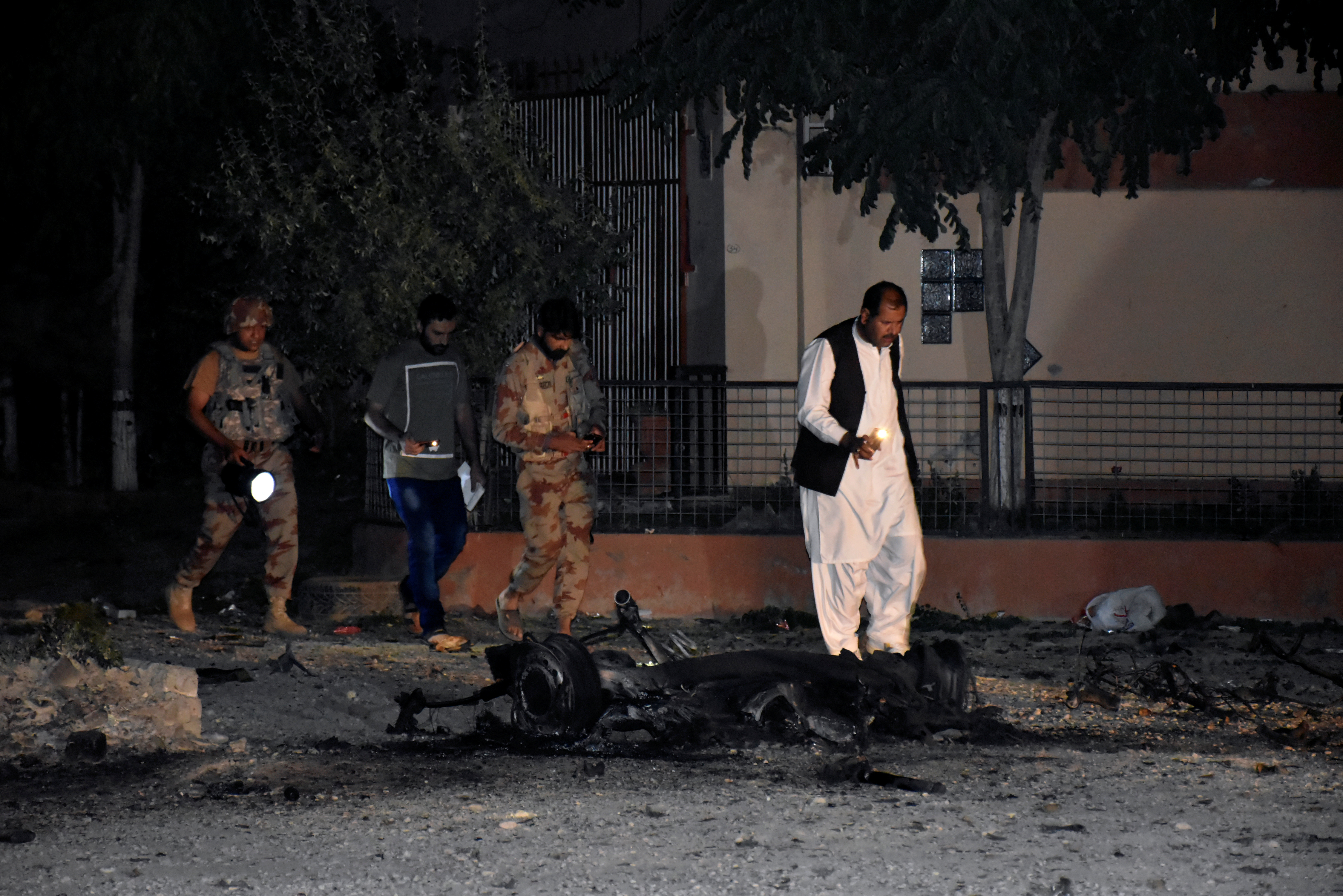 Security officers and paramilitary soldiers survey the site, after five suicide bombers tried to drive a vehicle laden with ammunition and explosives into a military facility in Quetta