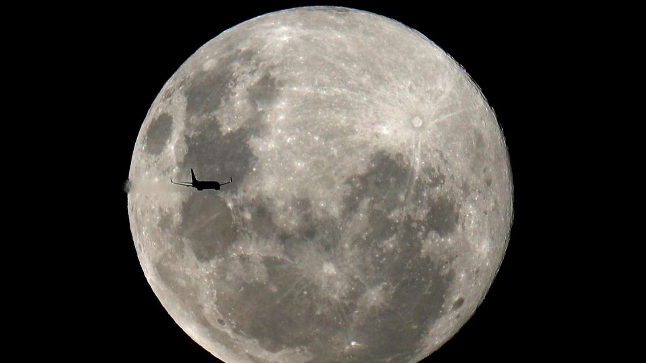 A plane is pictured in front of the full moon in Curitiba