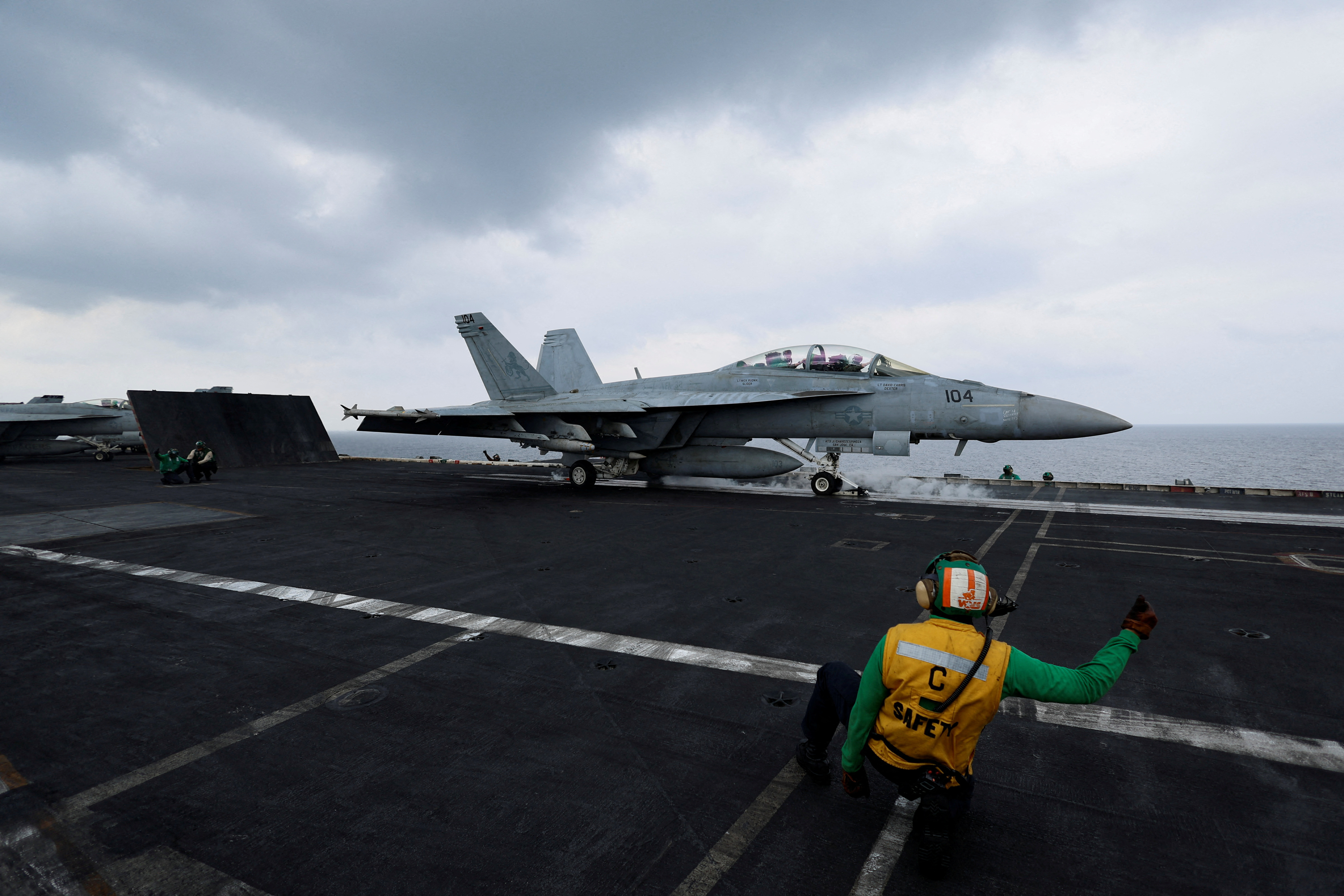 FILE PHOTO: A flight operating crew member signals a F/A-18E Super Hornet fighter jet on the flight deck of the USS Dwight D. Eisenhower (CVN 69) aircraft carrier in Southern Red Sea