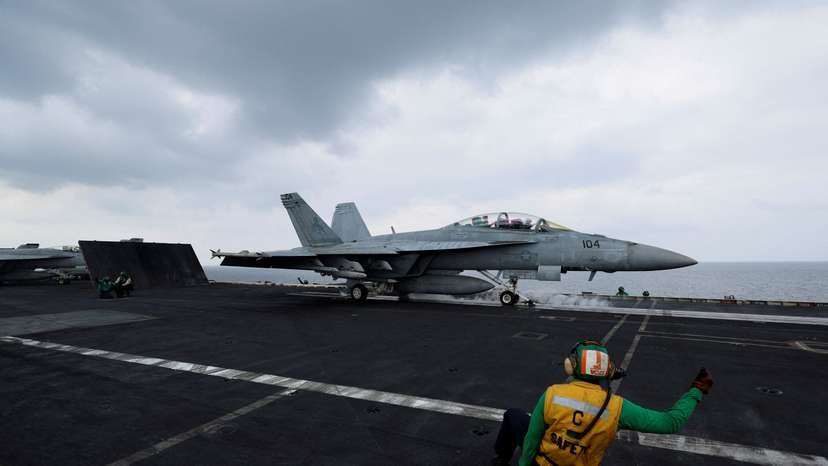 FILE PHOTO: A flight operating crew member signals a F/A-18E Super Hornet fighter jet on the flight deck of the USS Dwight D. Eisenhower (CVN 69) aircraft carrier in Southern Red Sea