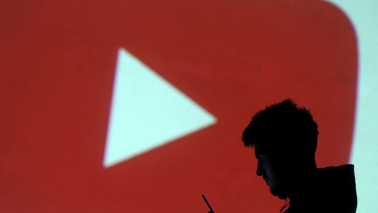 FILE PHOTO: A silhouette of a mobile user is seen next to a screen projection of Youtube logo in this picture illustration