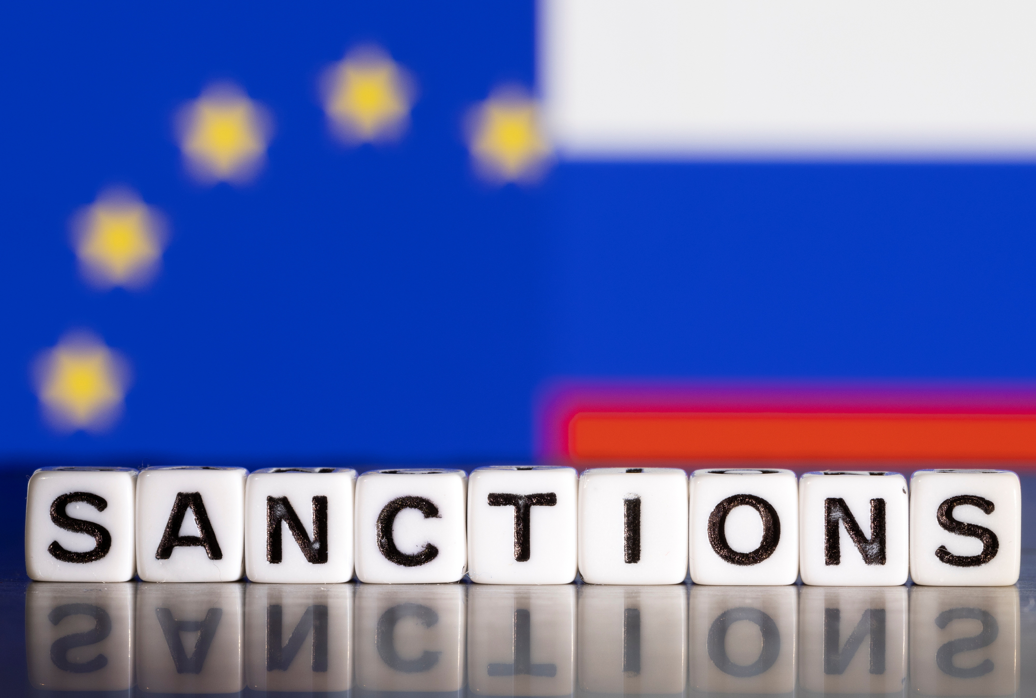 Illustration shows letters arranged to read "Sanctions" in front of flag colors of EU and Russia