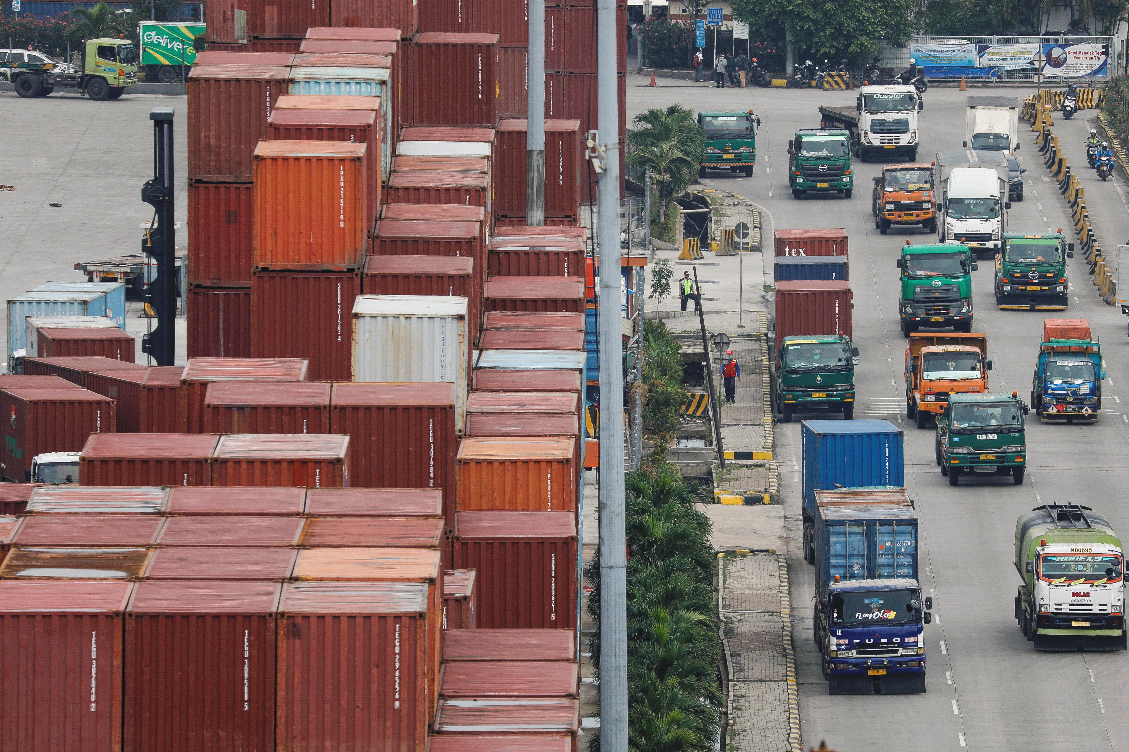 Trucks drive past stacks of containers at the Tanjung Priok port in Jakarta