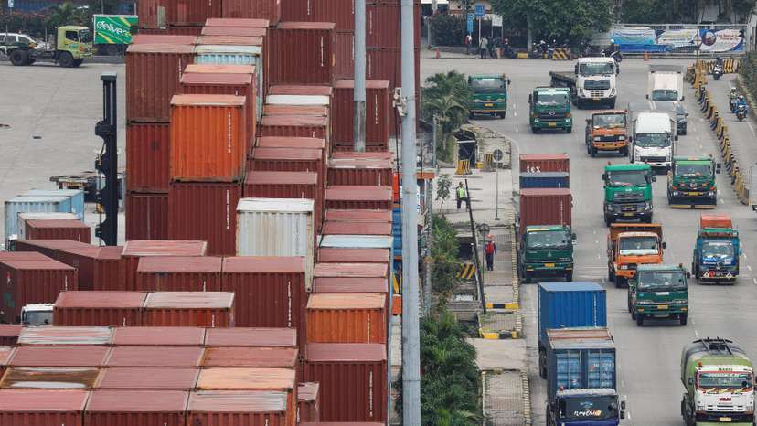 Trucks drive past stacks of containers at the Tanjung Priok port in Jakarta