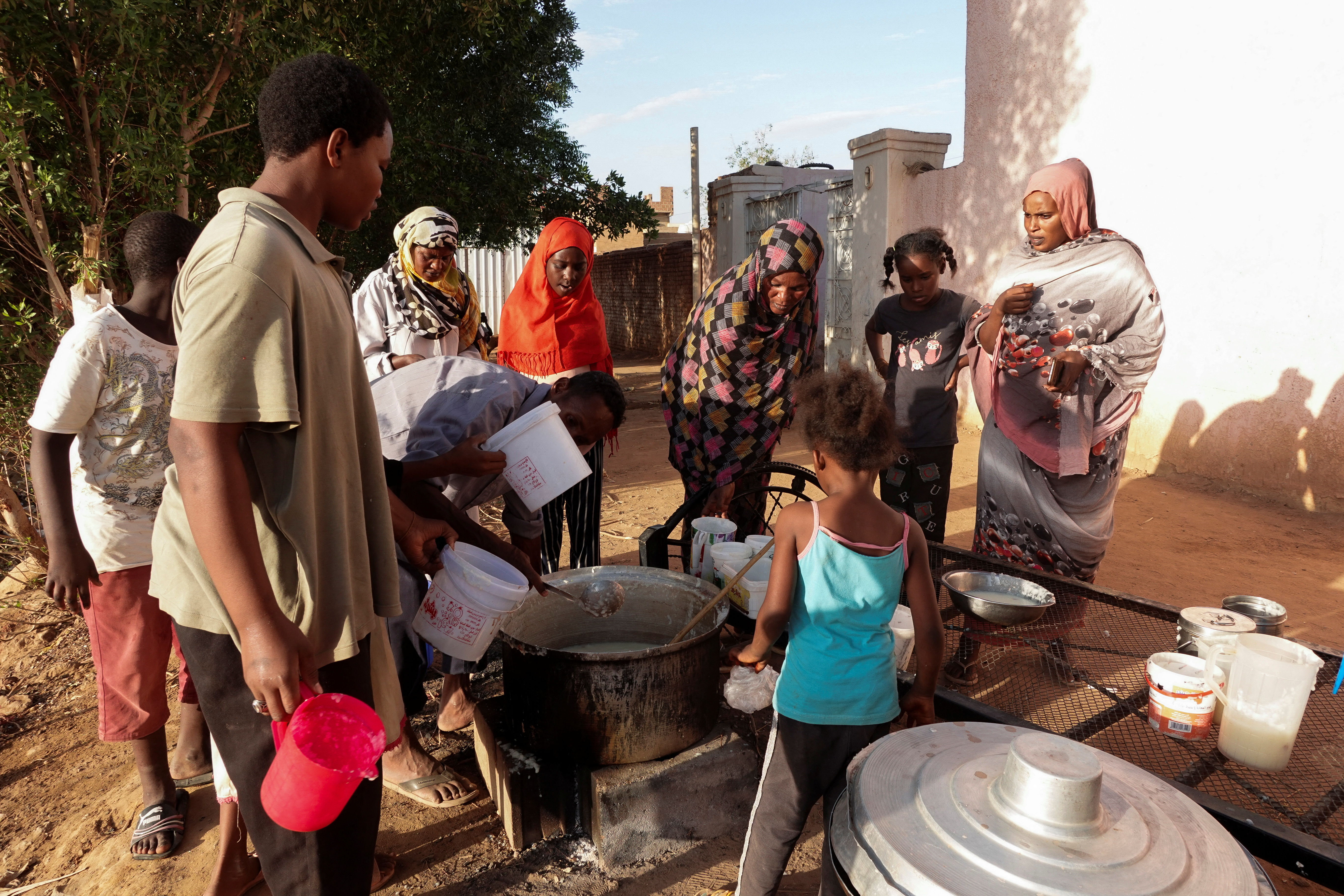 FILE PHOTO: Displaced Sudanese families wait to receive food from a charity kitchen, in the city of Omdurman