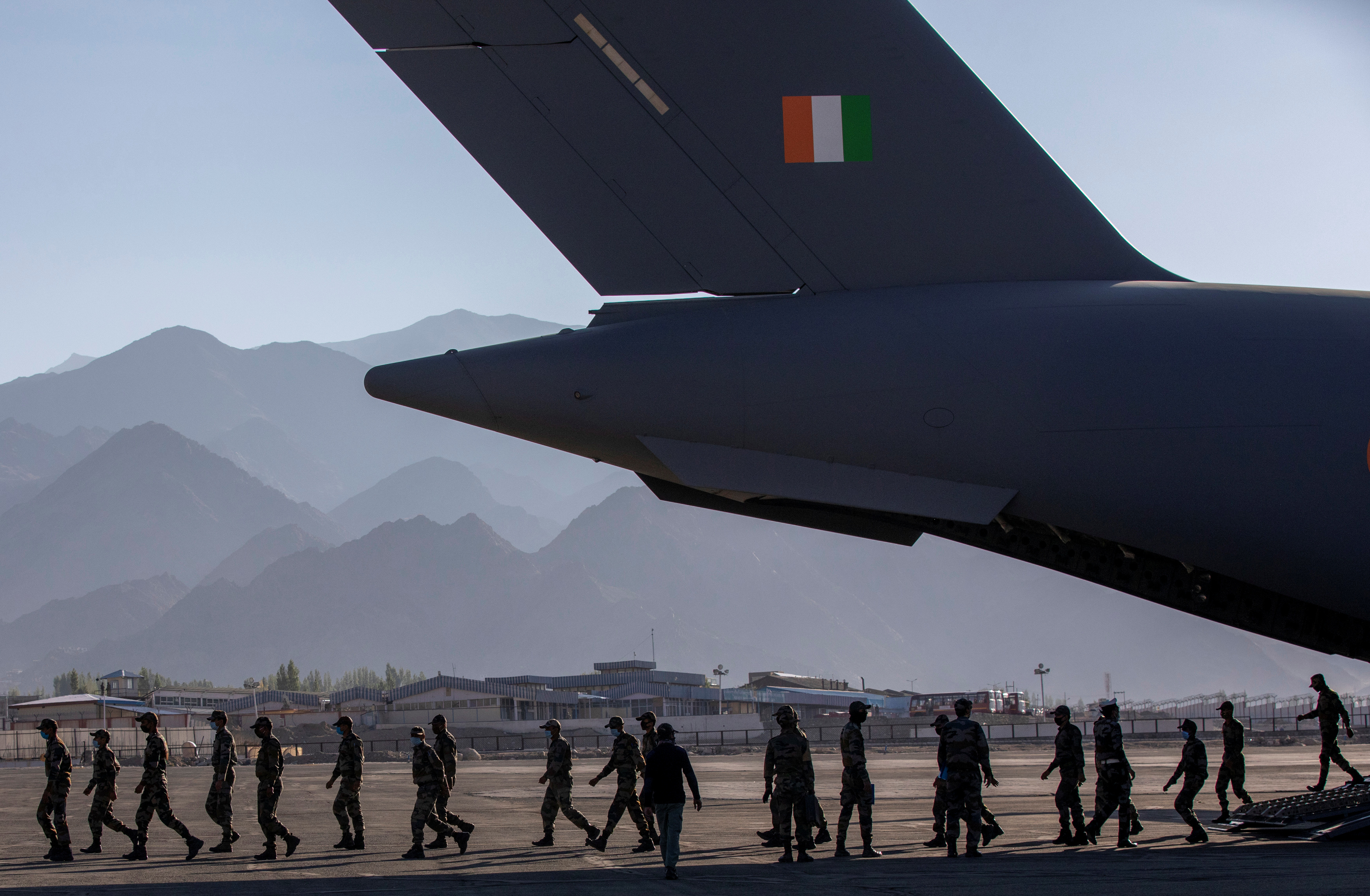Indian soldiers disembark from a military transport plane at a forward airbase in Leh