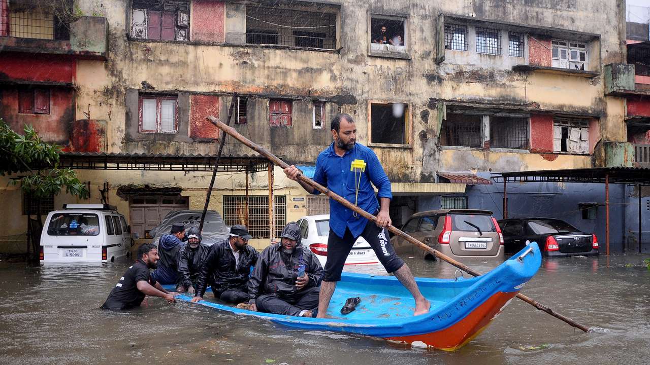 People move in a boat past partially submerged vehicles in Chennai