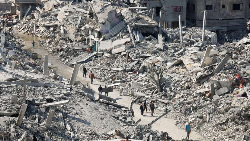 Palestinians walk past the rubble of destroyed buildings, amid a ceasefire between Israel and Hamas, in Gaza City