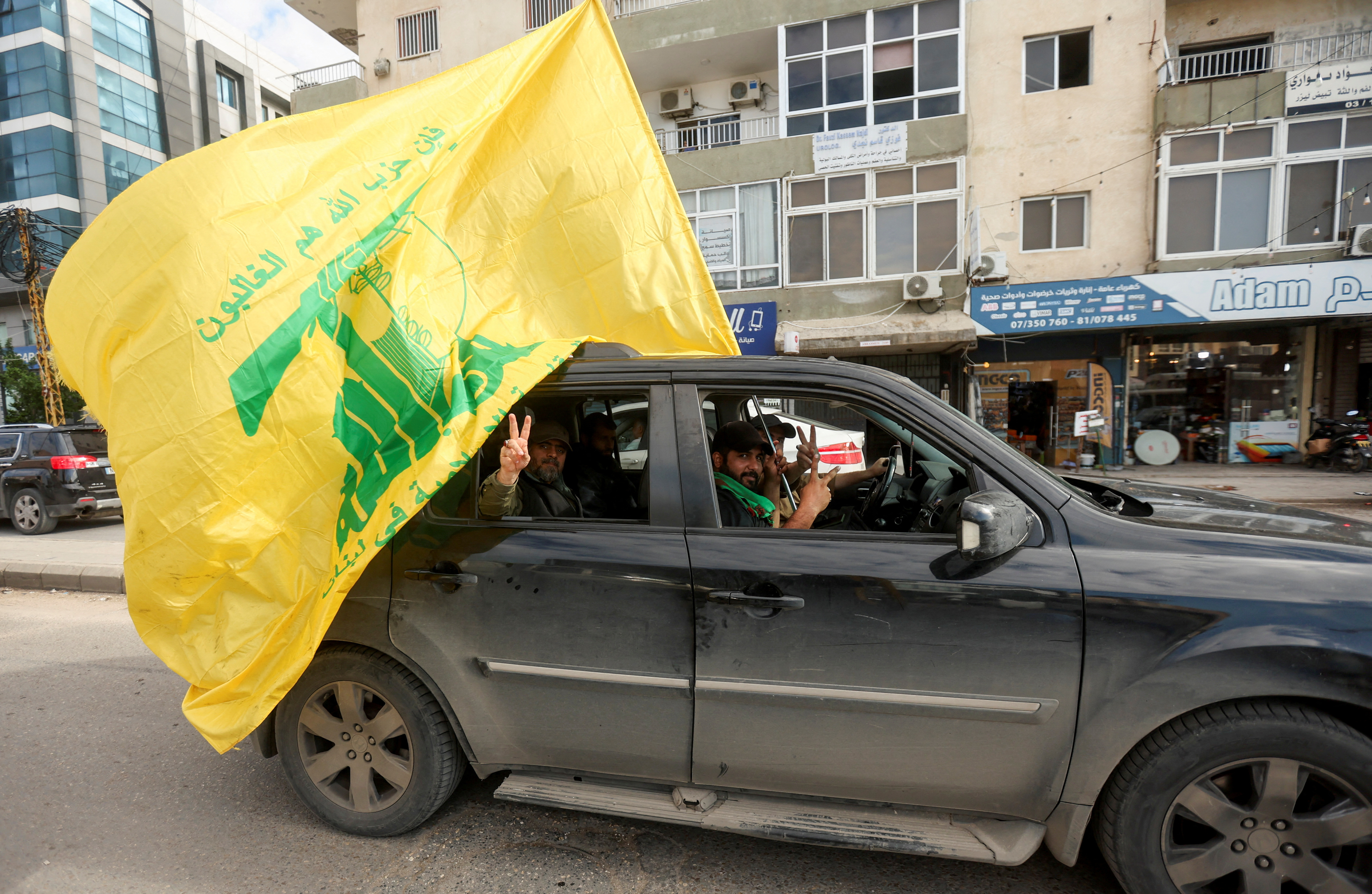 FILE PHOTO: A man gestures the victory sign as he holds a Hezbollah flag, in Tyre