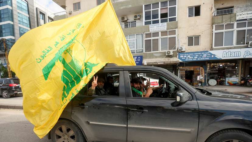 FILE PHOTO: A man gestures the victory sign as he holds a Hezbollah flag, in Tyre