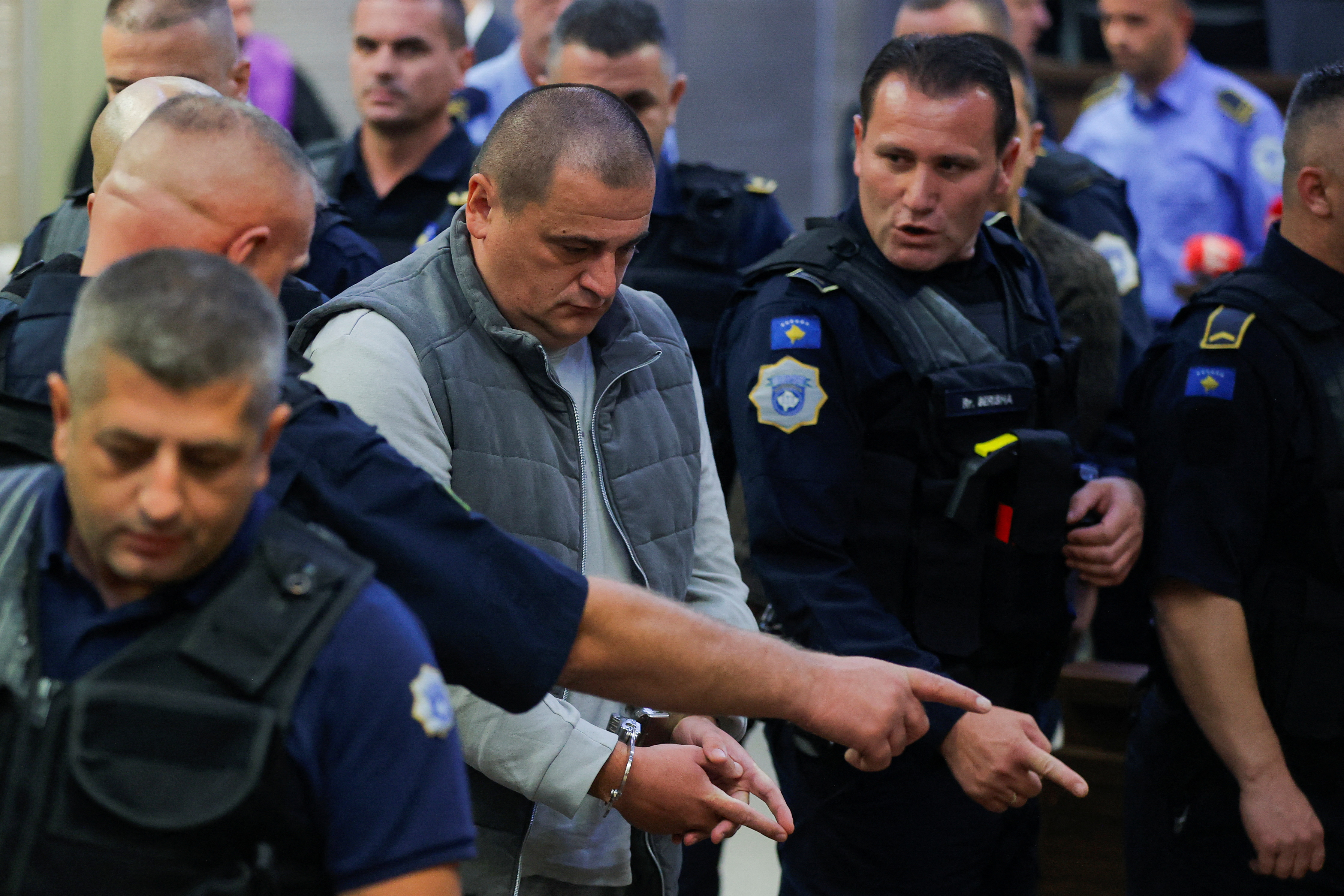 Kosovo police officers escort the alleged Serbian gunman Vladimir Tolic at the basic court in Pristina