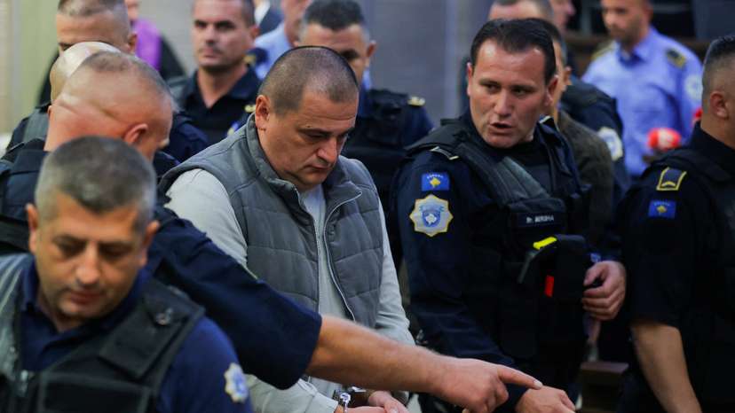 Kosovo police officers escort the alleged Serbian gunman Vladimir Tolic at the basic court in Pristina