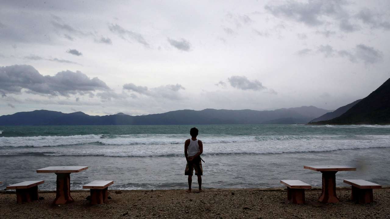 FILE PHOTO: A resort worker looks out at a beach at an empty resort as Typhoon Haima strikes Pagudpud