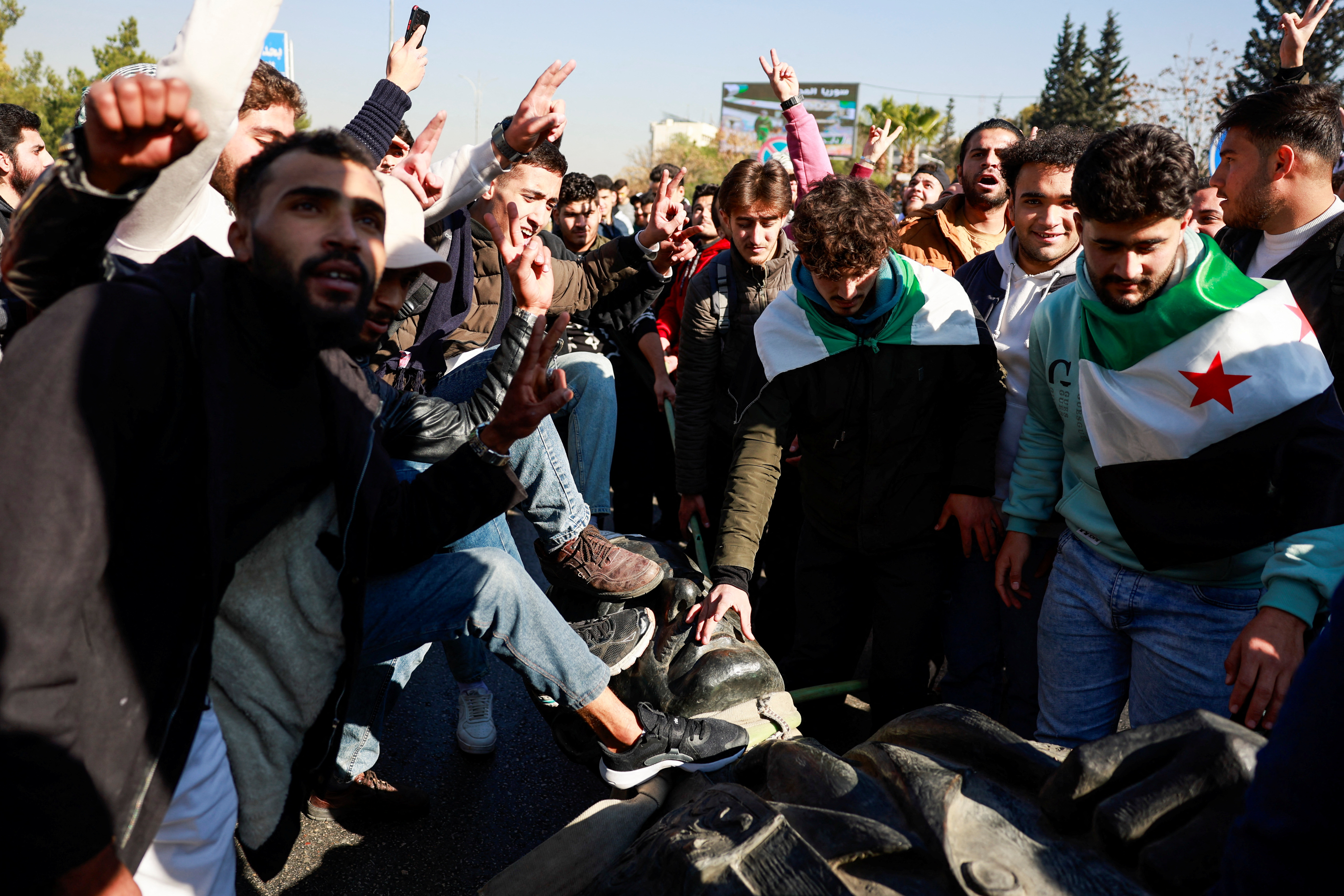 People damage a statue of the late Syria's President Hafez al-Assad, father of Bashar al-Assad, in Damascus