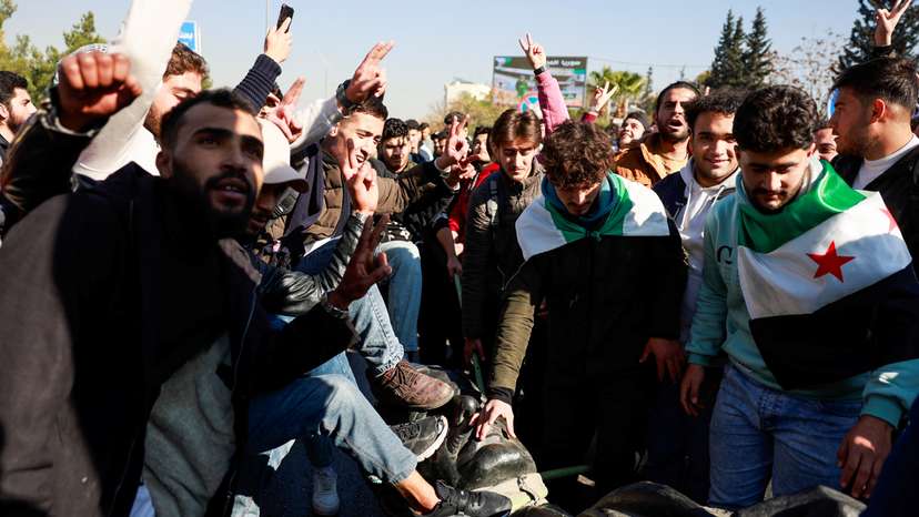 People damage a statue of the late Syria's President Hafez al-Assad, father of Bashar al-Assad, in Damascus