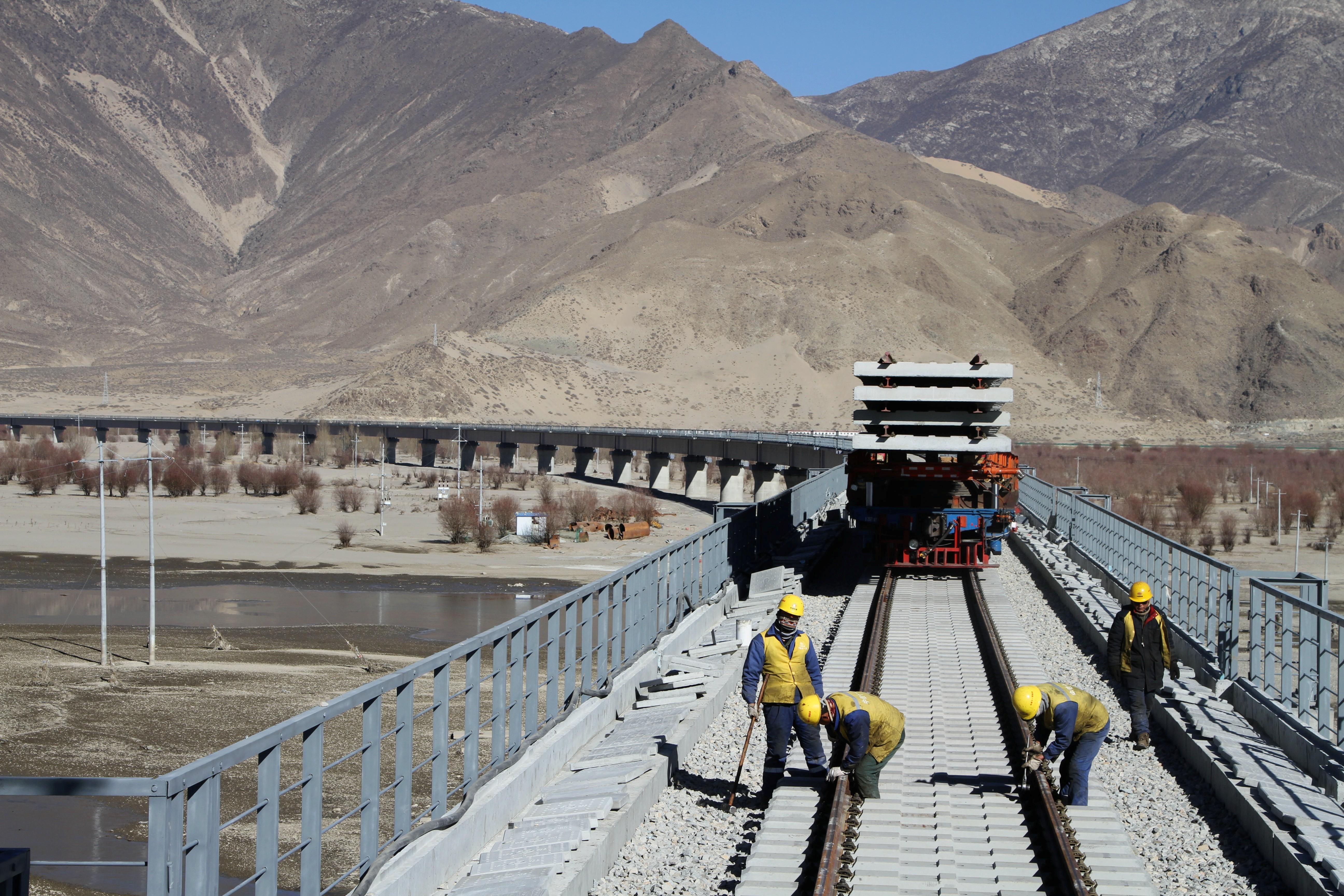 Workers are seen on railway tracks at a bridge over Yarlung Tsangpo river as they work on the construction of the railroad linking Lhasa and Nyingchi