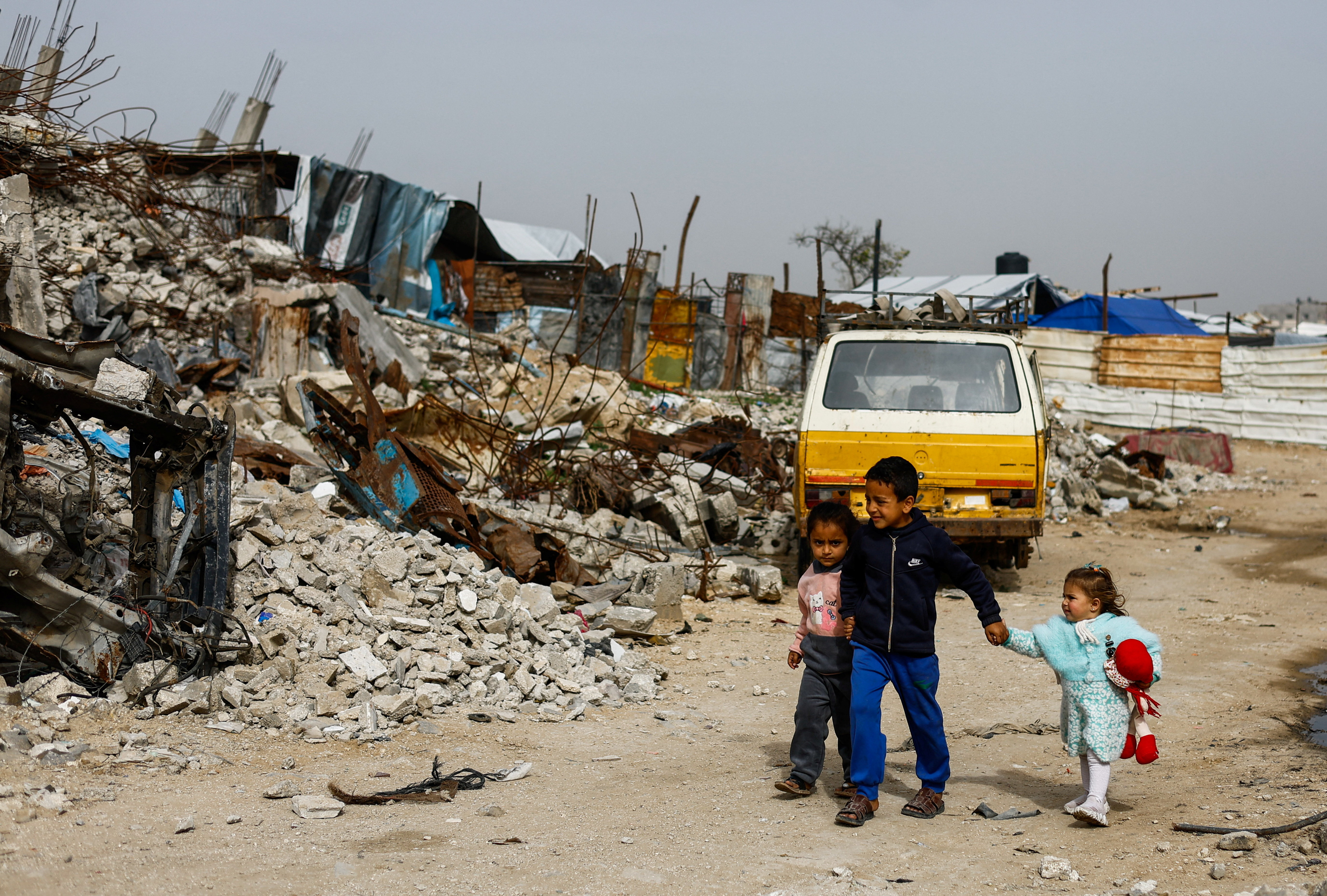 Palestinians walk past the rubble of residential buildings destroyed during the war, in Gaza City