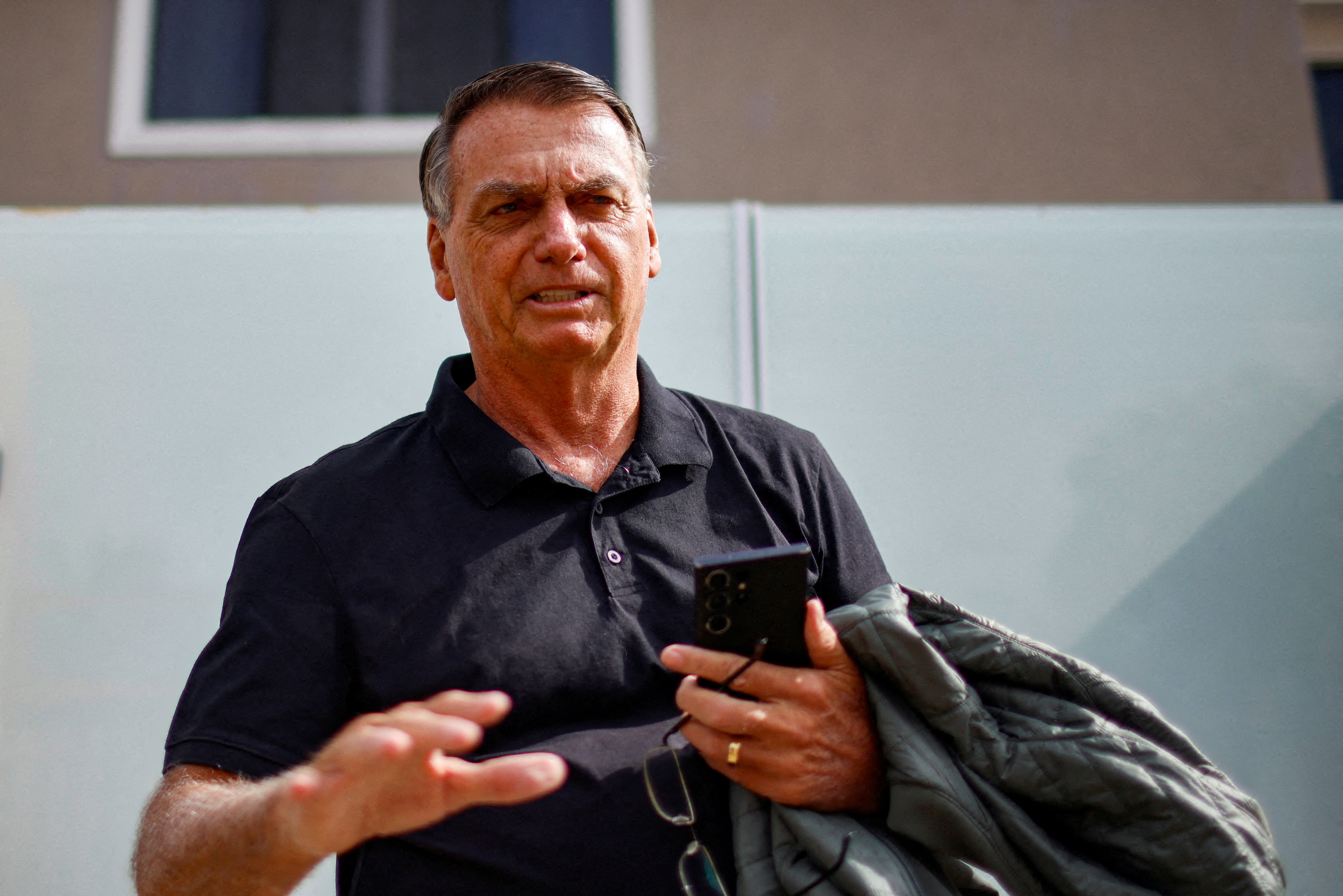 FILE PHOTO: Former Brazilian President Jair Bolsonaro gestures while standing in front of his house before testifying to the Federal Police in Brasilia