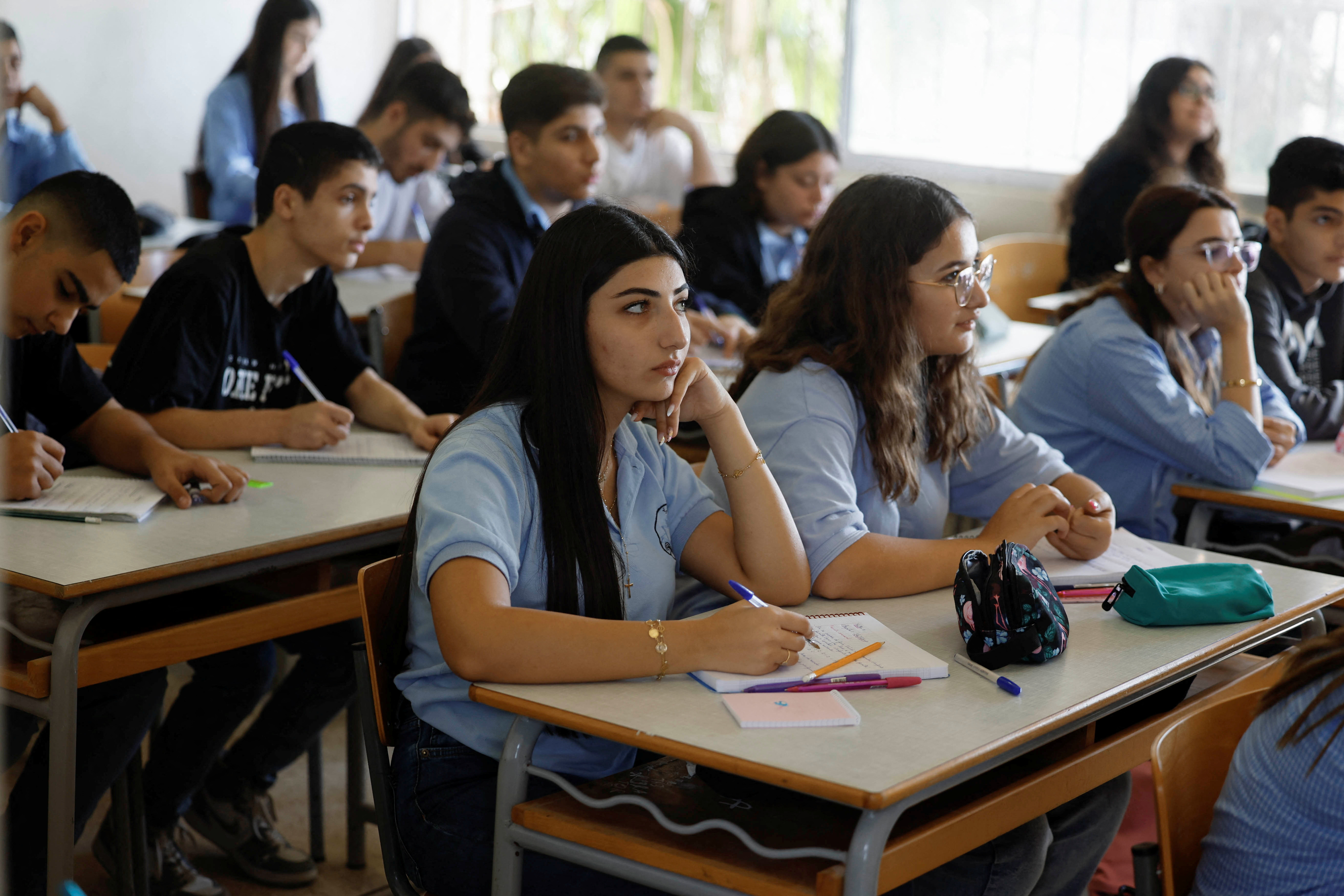 Lebanese students attend lessons at a public school, which is hosting displaced people in one of its buildings, in Amchit