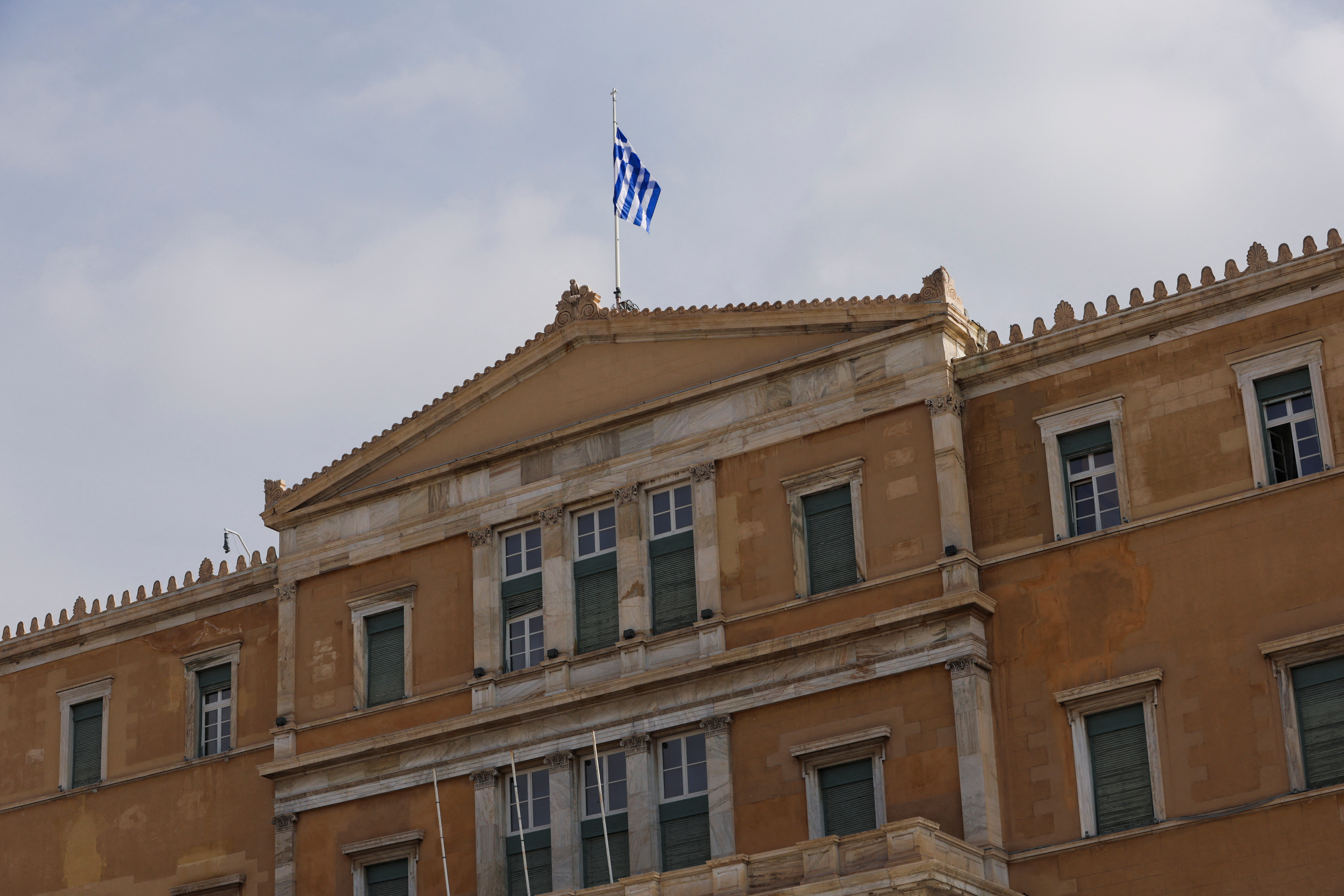 A Greek flag flutters atop the parliament building in Athens
