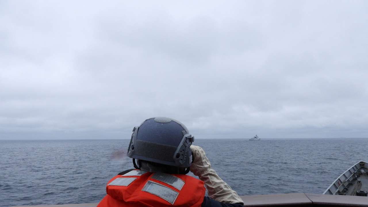 A Taiwanese sailor aboard a Taiwan Navy vessel looks towards a Chinese warship while navigating on waters off Taiwan's western coast