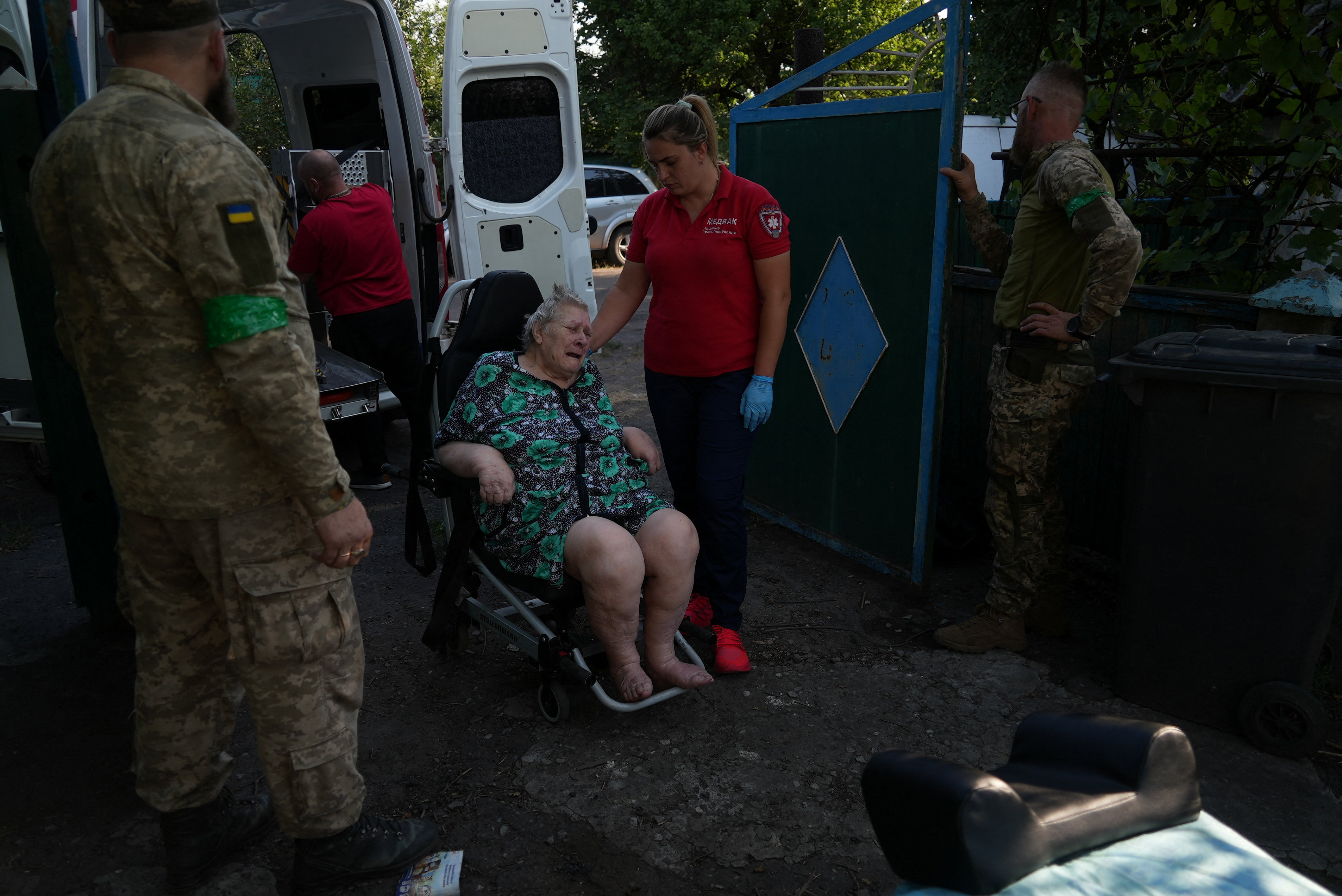 Ukrainian servicemen help volunteers to evacuate a resident from the frontline town of Dobropillia