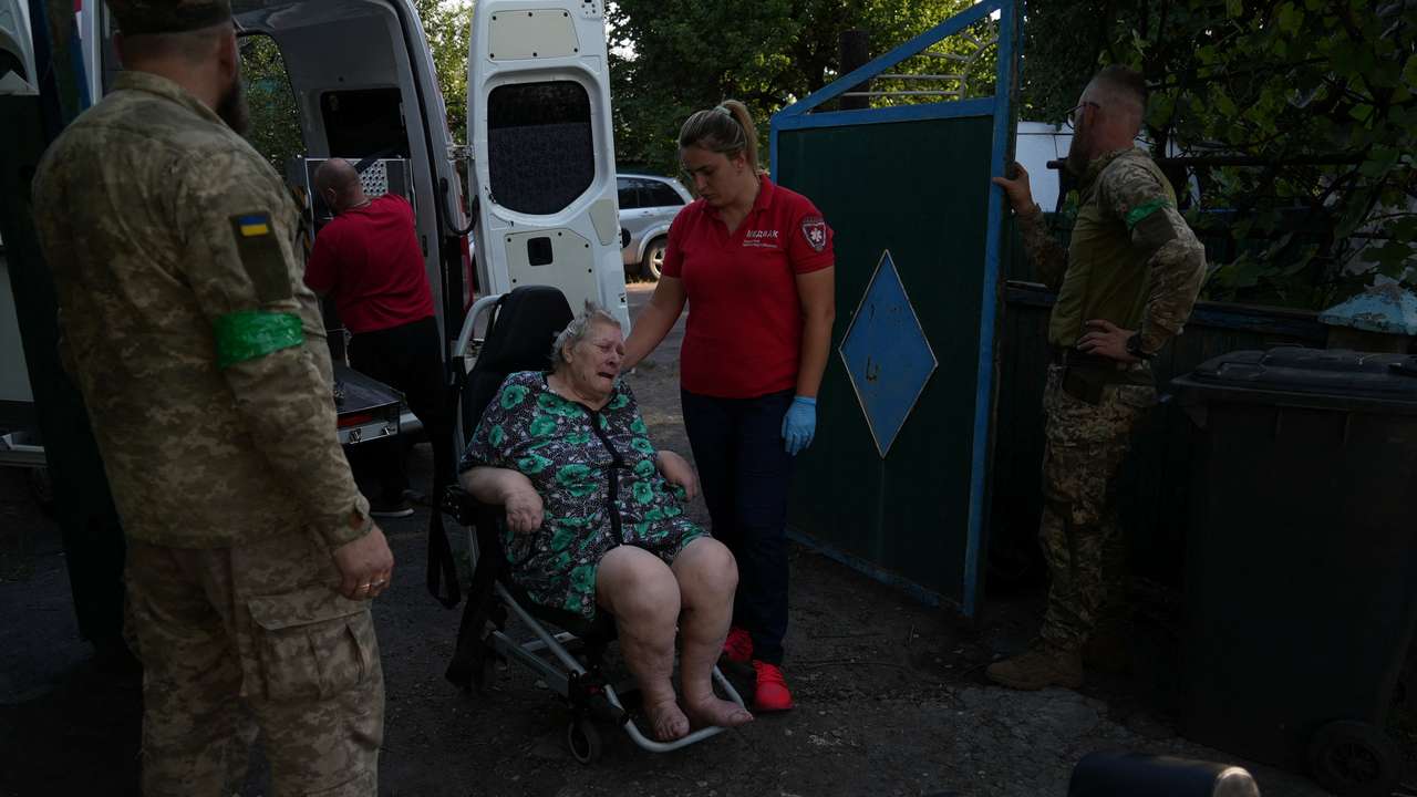 Ukrainian servicemen help volunteers to evacuate a resident from the frontline town of Dobropillia