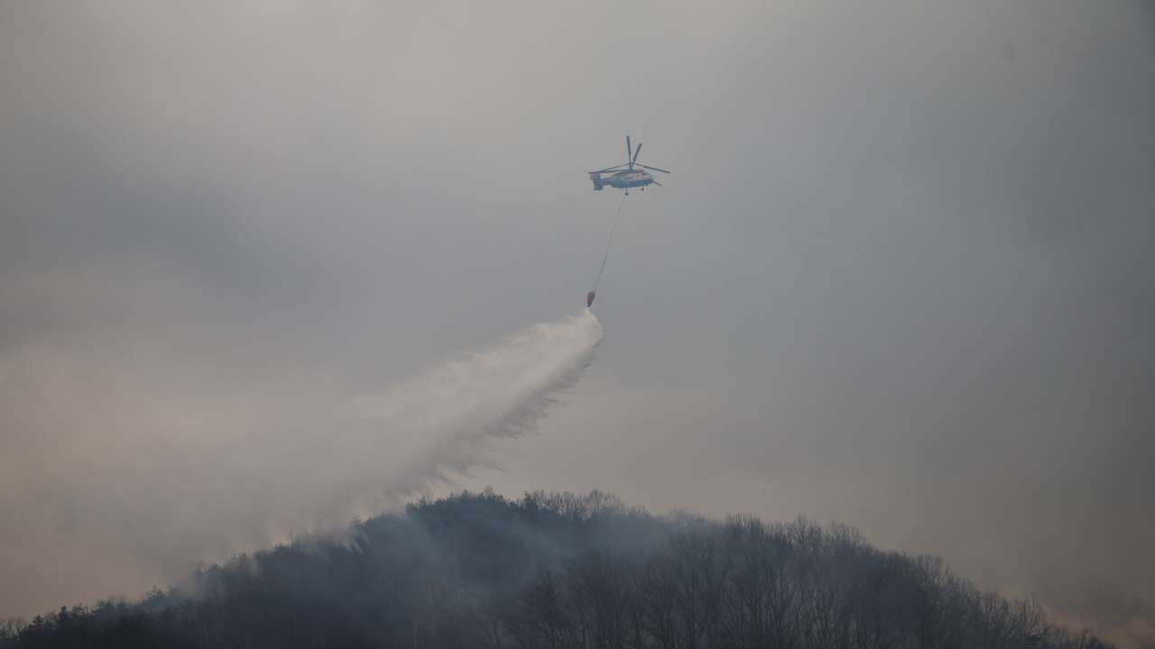 A firefighting helicopter flies during an operation as a wildfire burns, in Uiseong