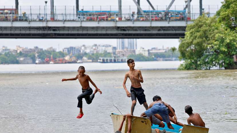 A boy jumps off a boat into the Ganges river to cool off on a hot summer day in Kolkata