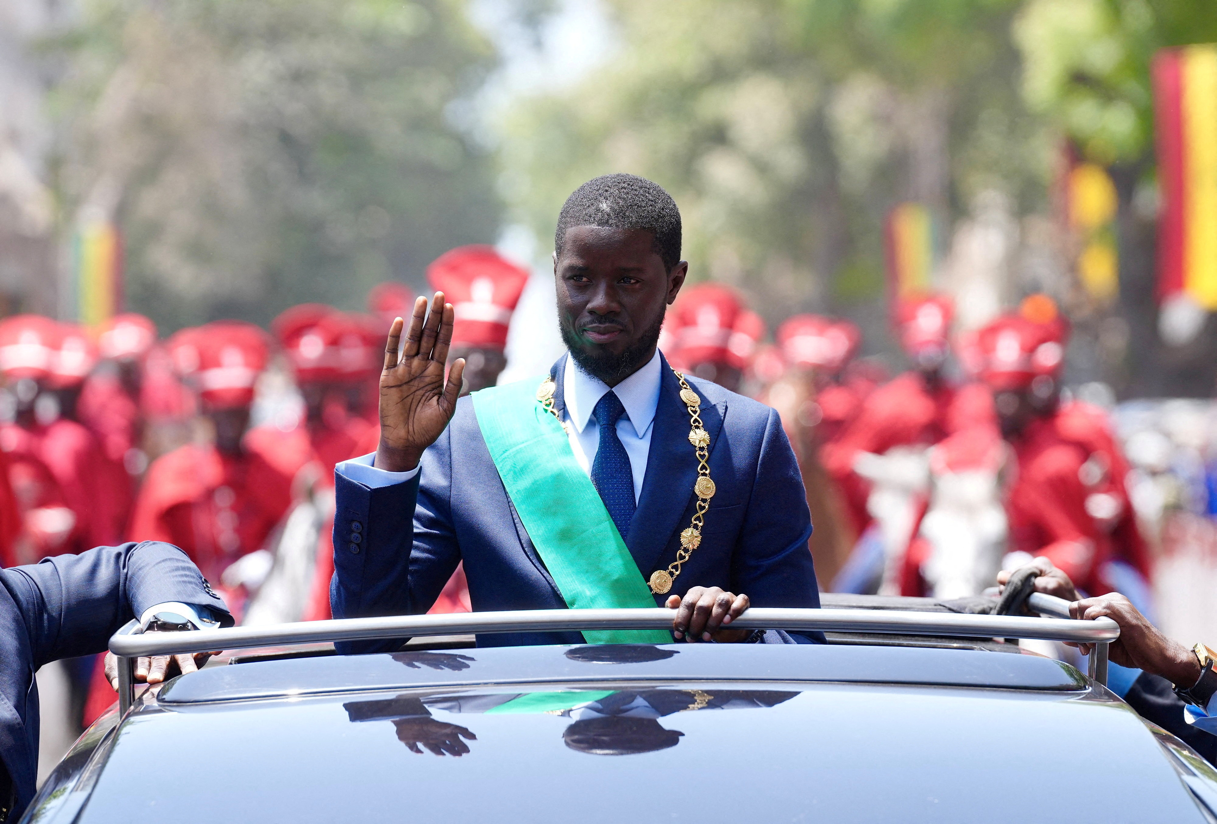 Senegal's newly-elected President Bassirou Diomaye Faye waves to supporters from a car after taking an oath of office as president during the inauguration ceremony in Dakar