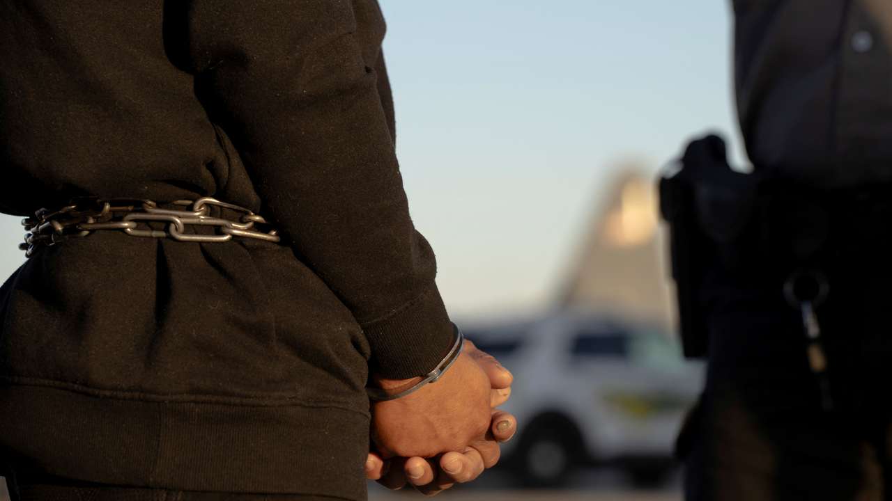 U.S. Customs and Border Protection security agents guide a group of detained migrants to board a removal flight