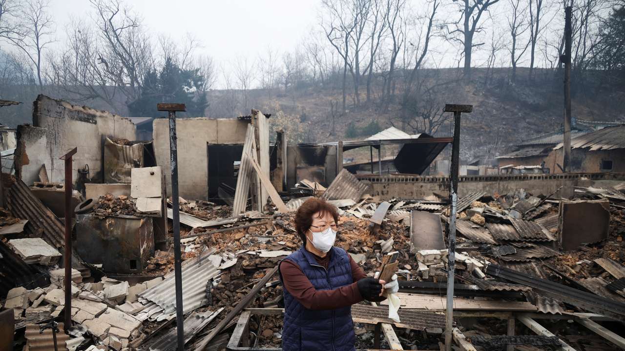 Kun Yeong-nam, 72, uses her mobile phone near her burnt house after a wildfire devastated the area in Uiseong