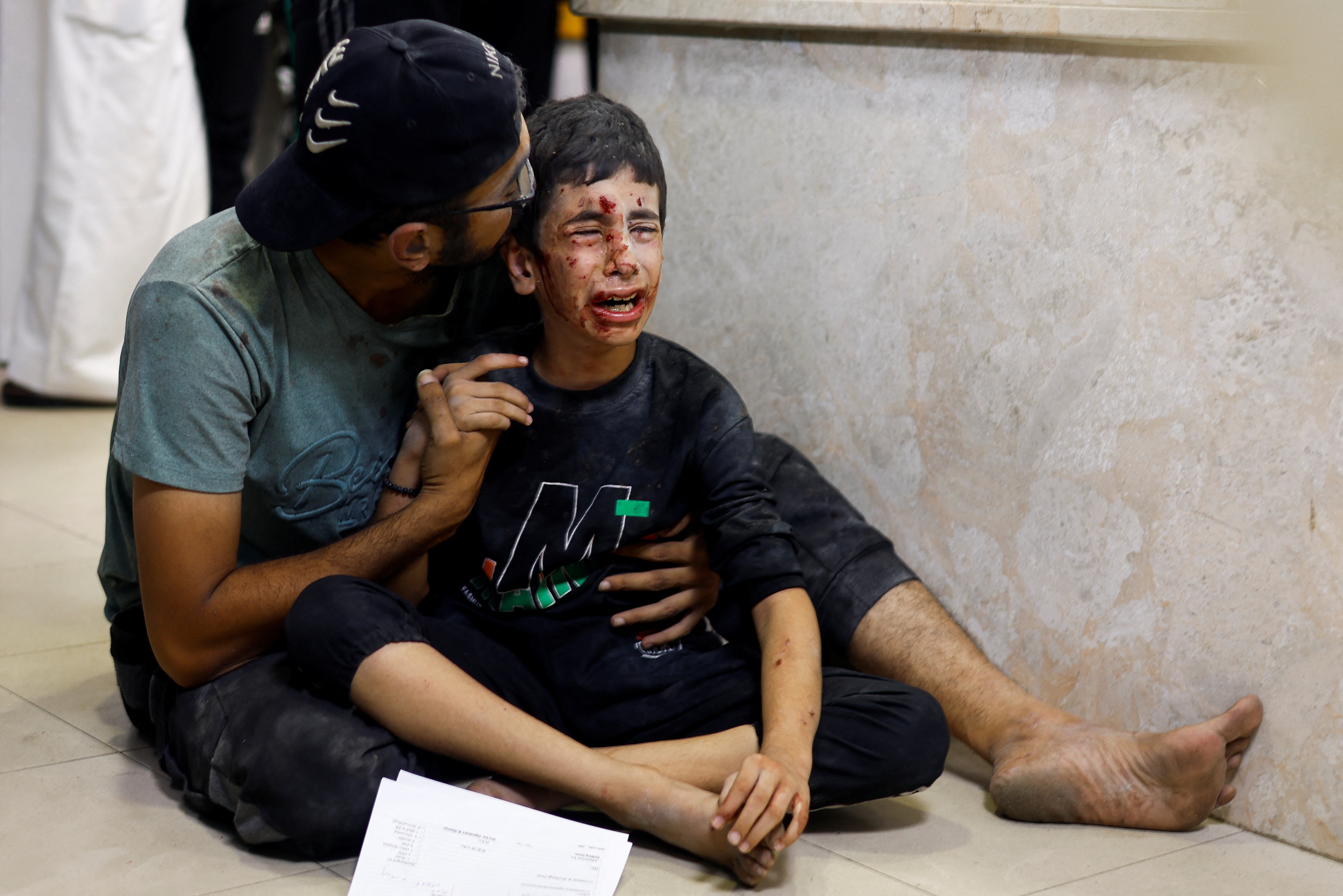 A Palestinian man sits with a child wounded in an Israeli strike at Nasser hospital in Khan Younis