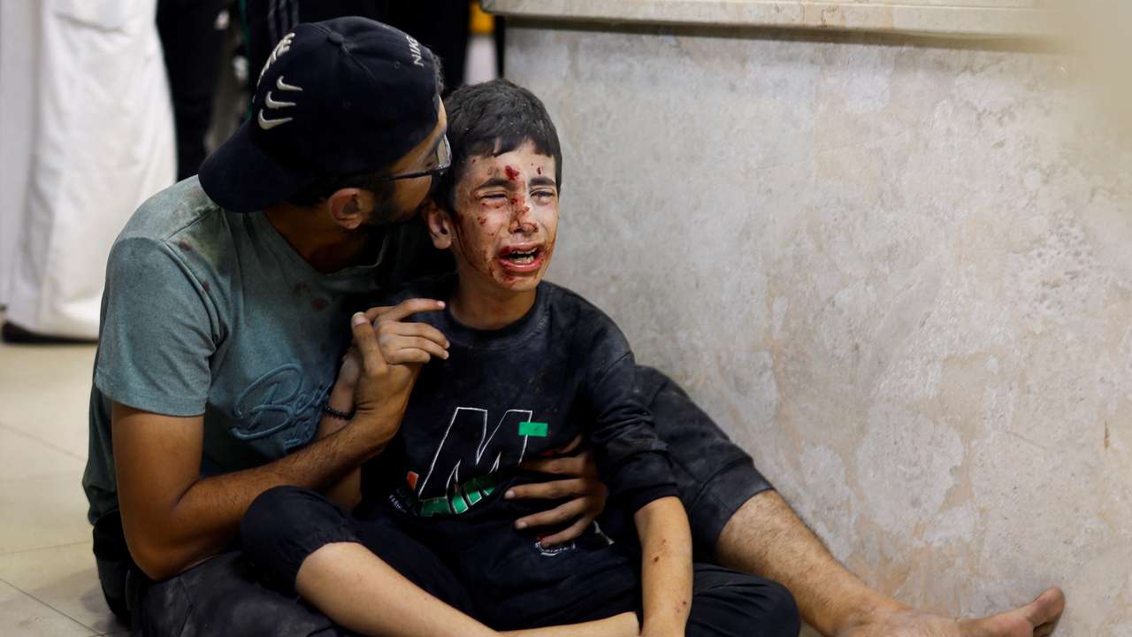 A Palestinian man sits with a child wounded in an Israeli strike at Nasser hospital in Khan Younis