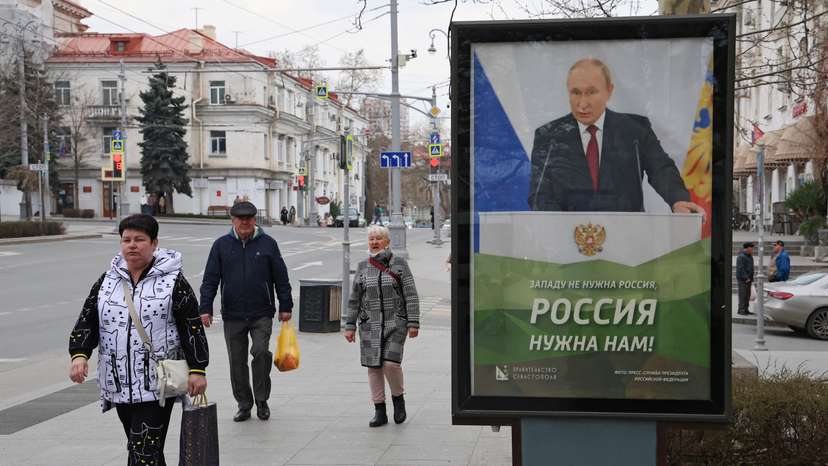 FILE PHOTO: People walk past a banner depicting Russian President Putin in Sevastopol