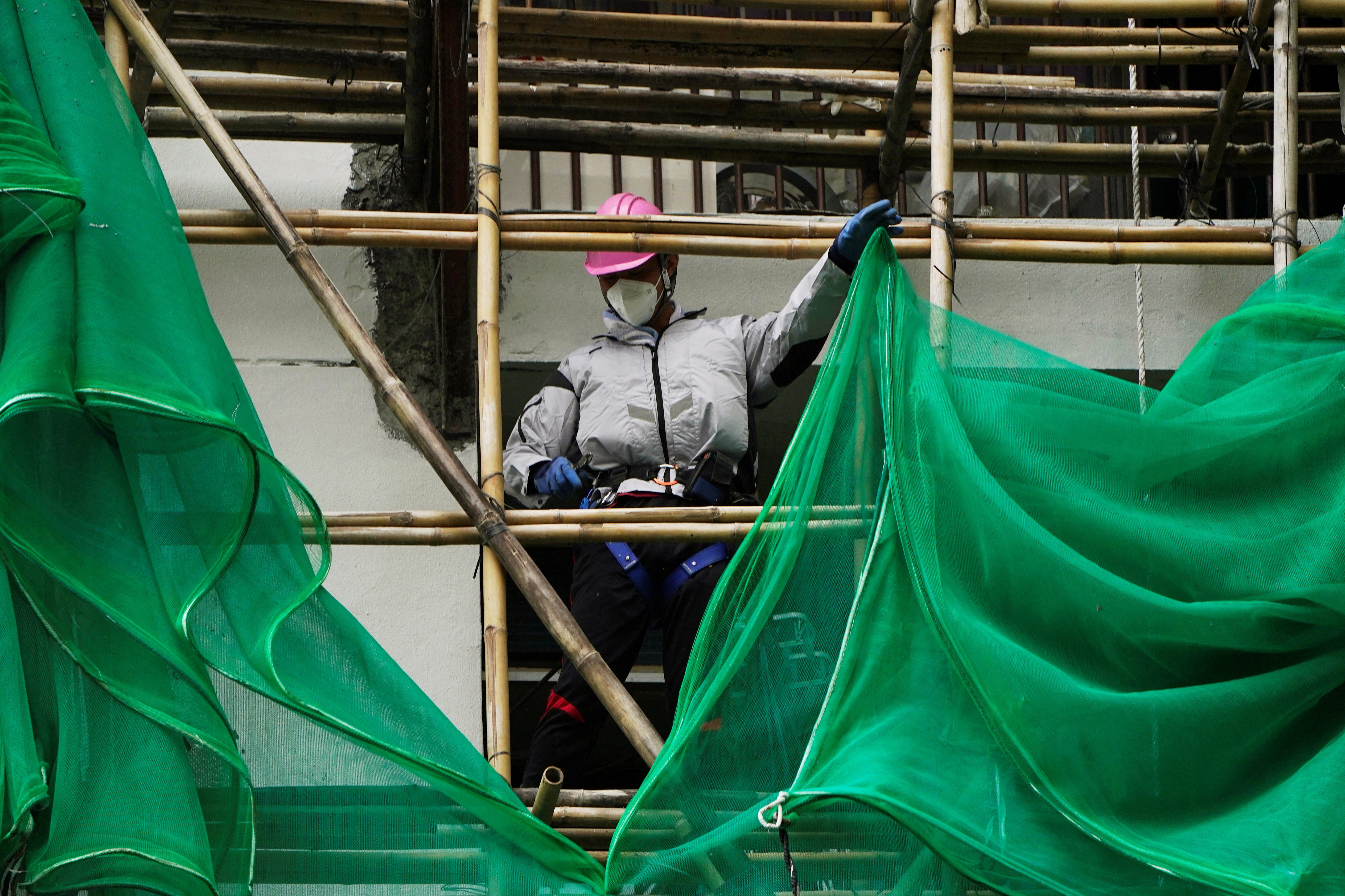 Worker removes scaffolding mesh from a building at Sui Wo Court in Hong Kong